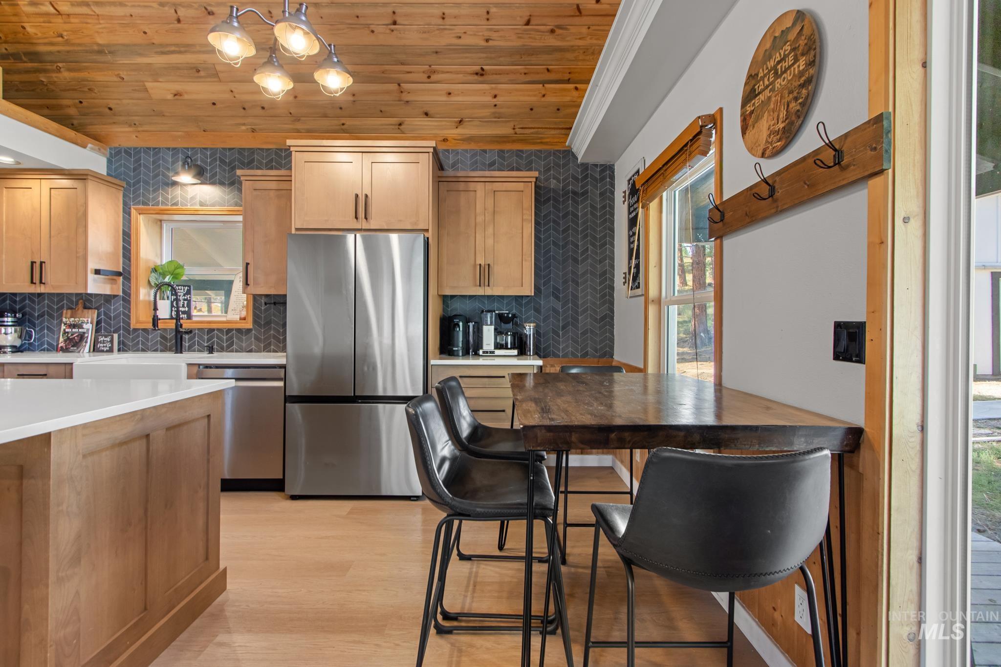 Kitchen featuring wood ceiling, appliances with stainless steel finishes, tasteful backsplash, light wood-style floors, and light brown cabinets