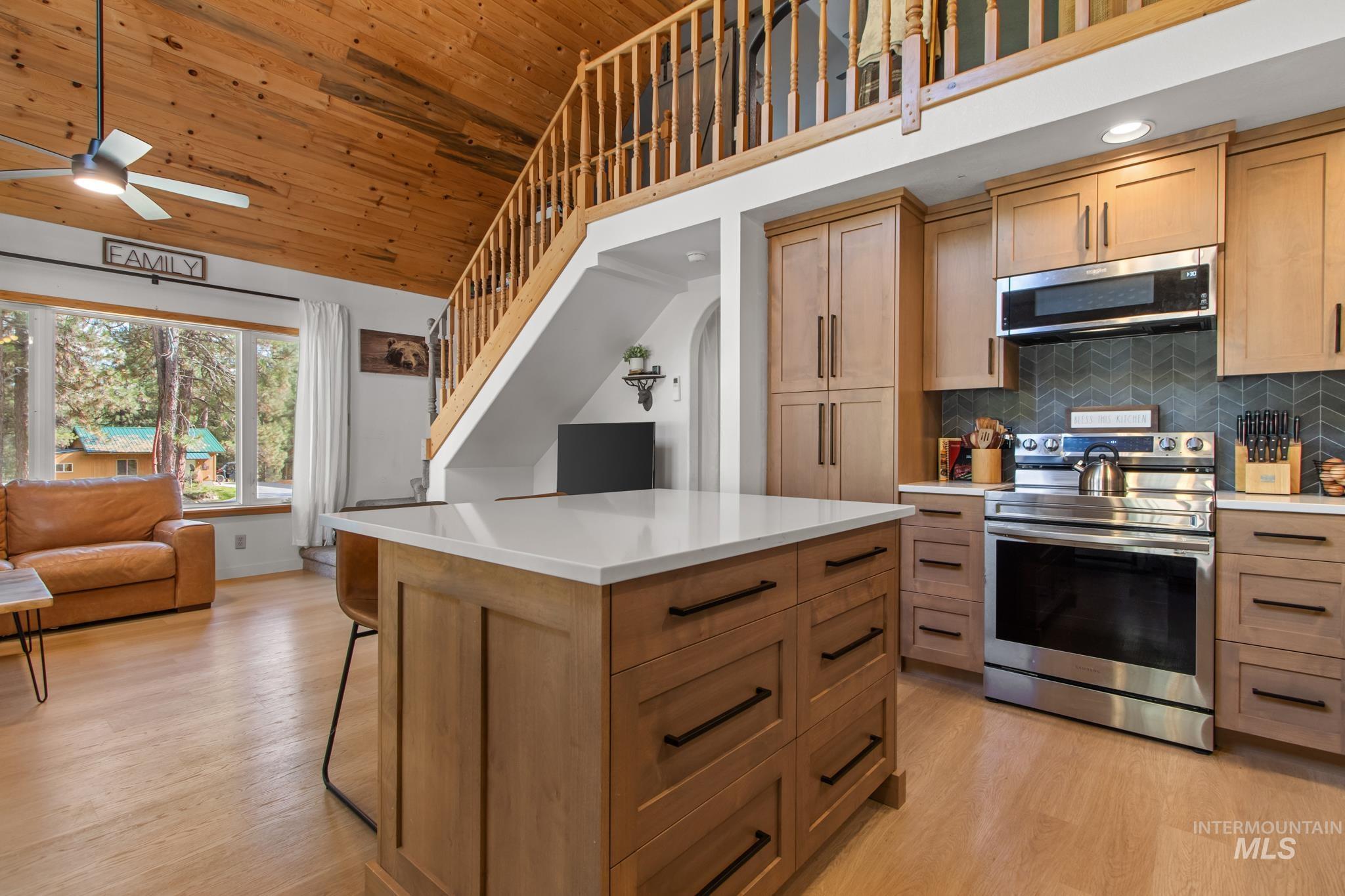 Kitchen featuring appliances with stainless steel finishes, backsplash, wood ceiling, light wood finished floors, and a center island