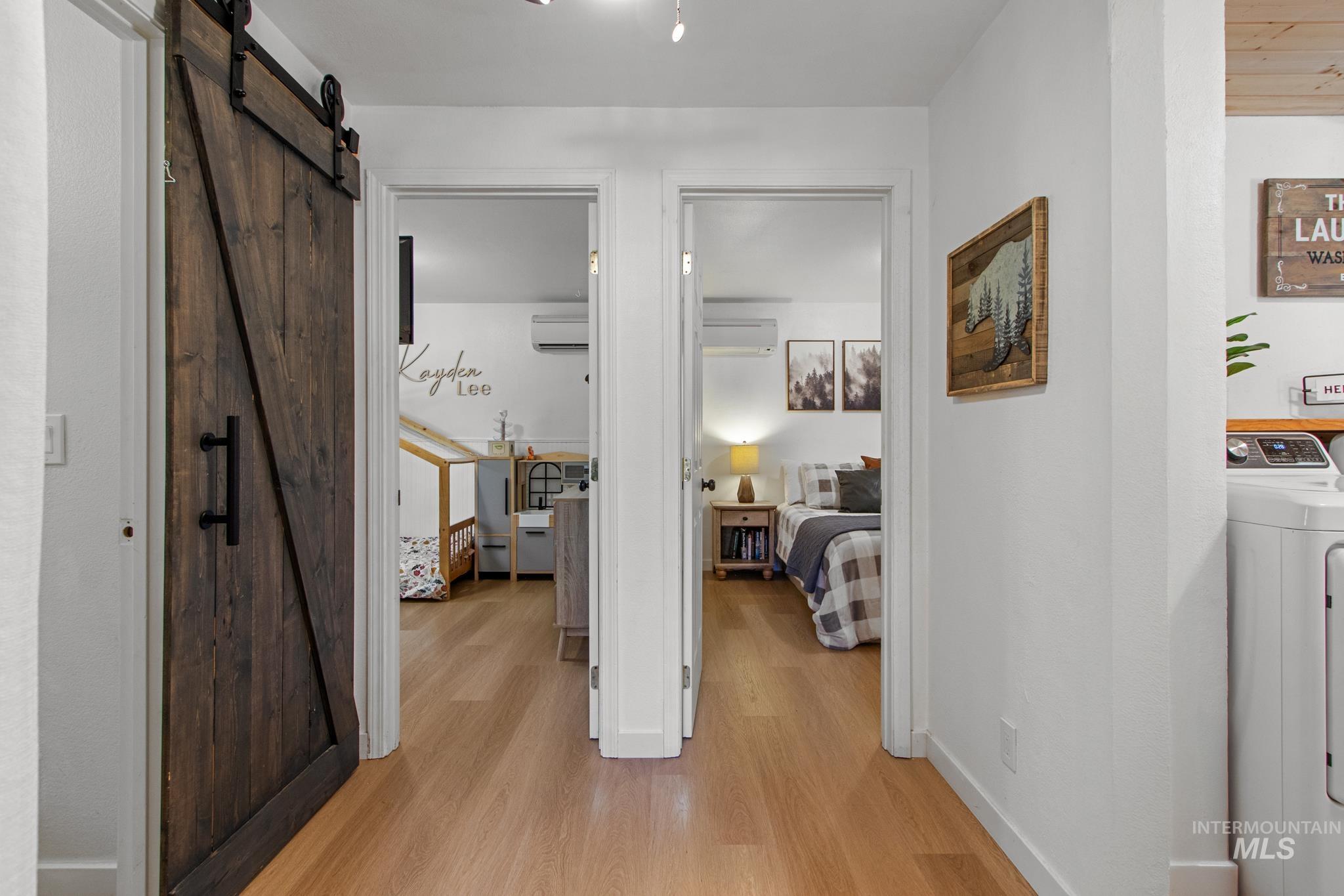 Hall with a barn door, light wood-style floors, and washer / clothes dryer