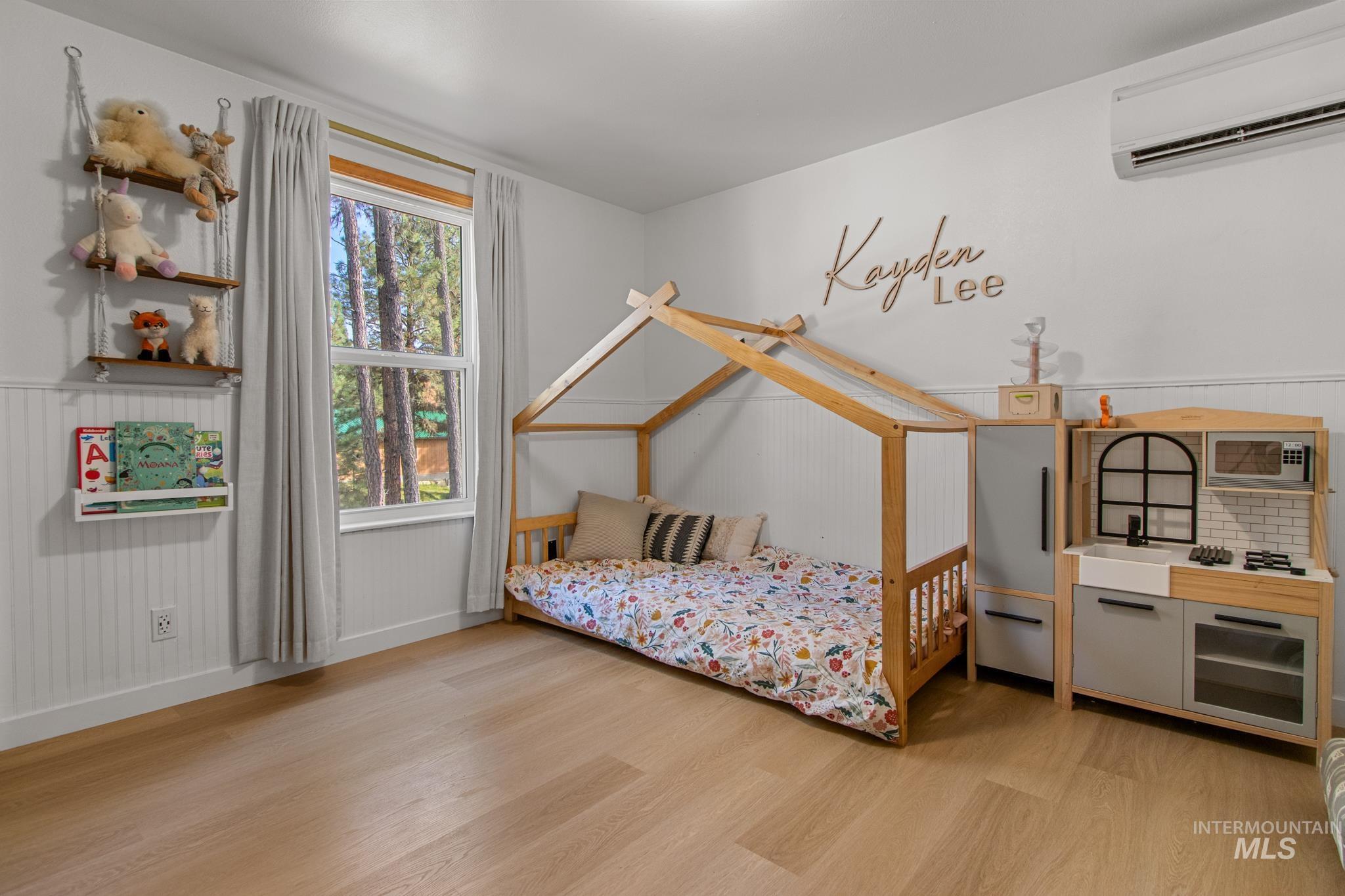 Bedroom with light wood-style flooring and a wall mounted AC