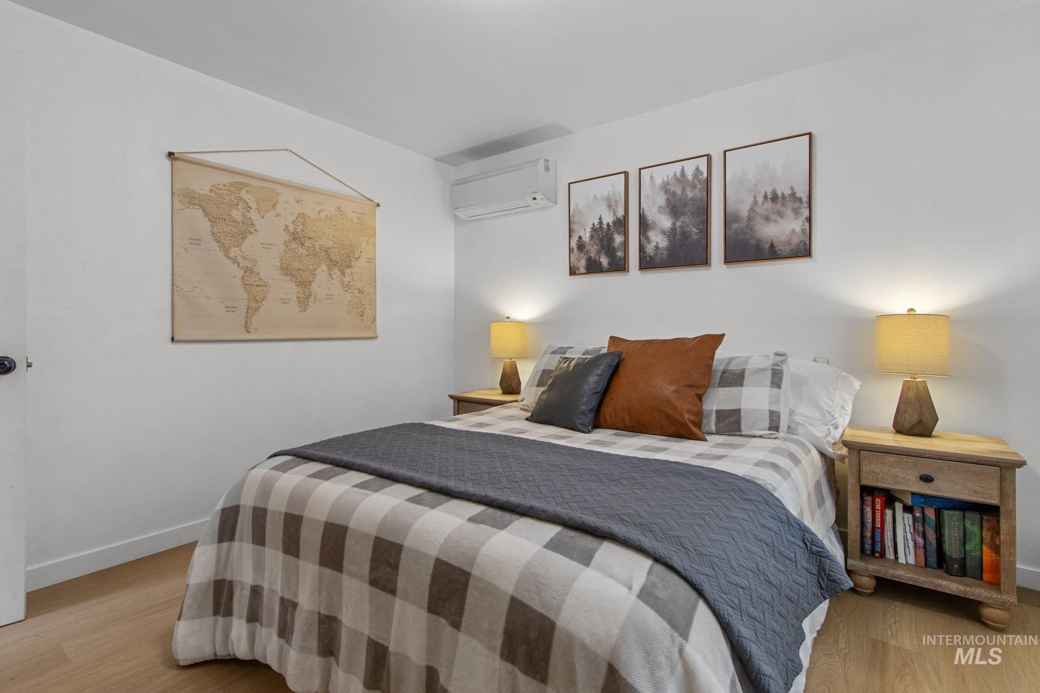 Bedroom with light wood finished floors and a wall unit AC