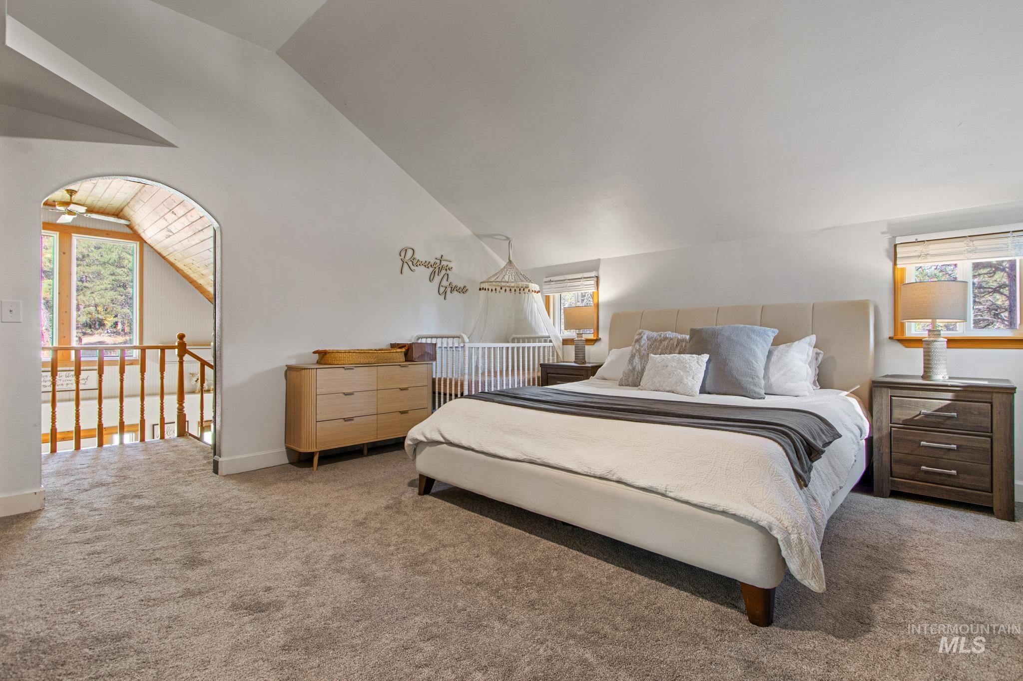 Carpeted bedroom with multiple windows and lofted ceiling