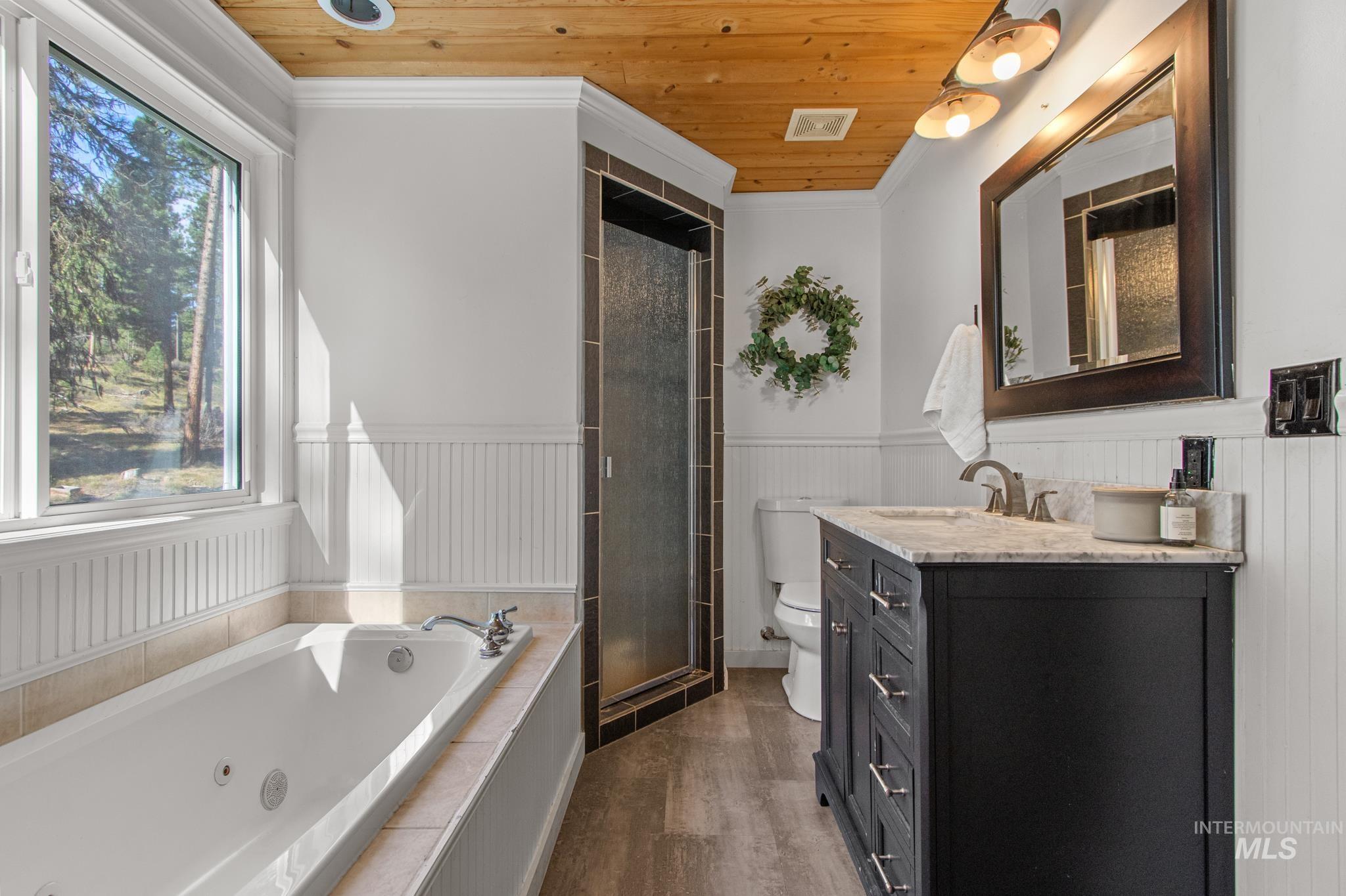 Full bath with a jetted tub, wood ceiling, crown molding, dark wood-style floors, and vanity