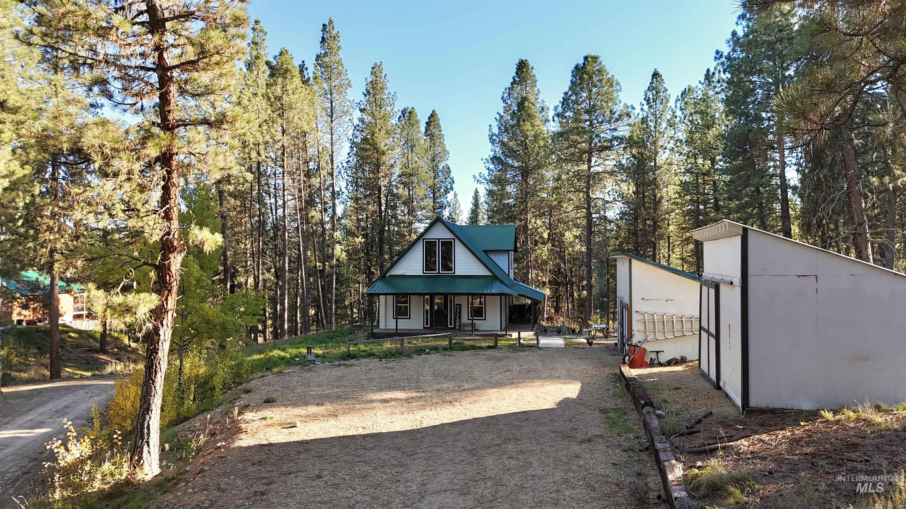 View of yard with covered porch, a forest view, and an outbuilding