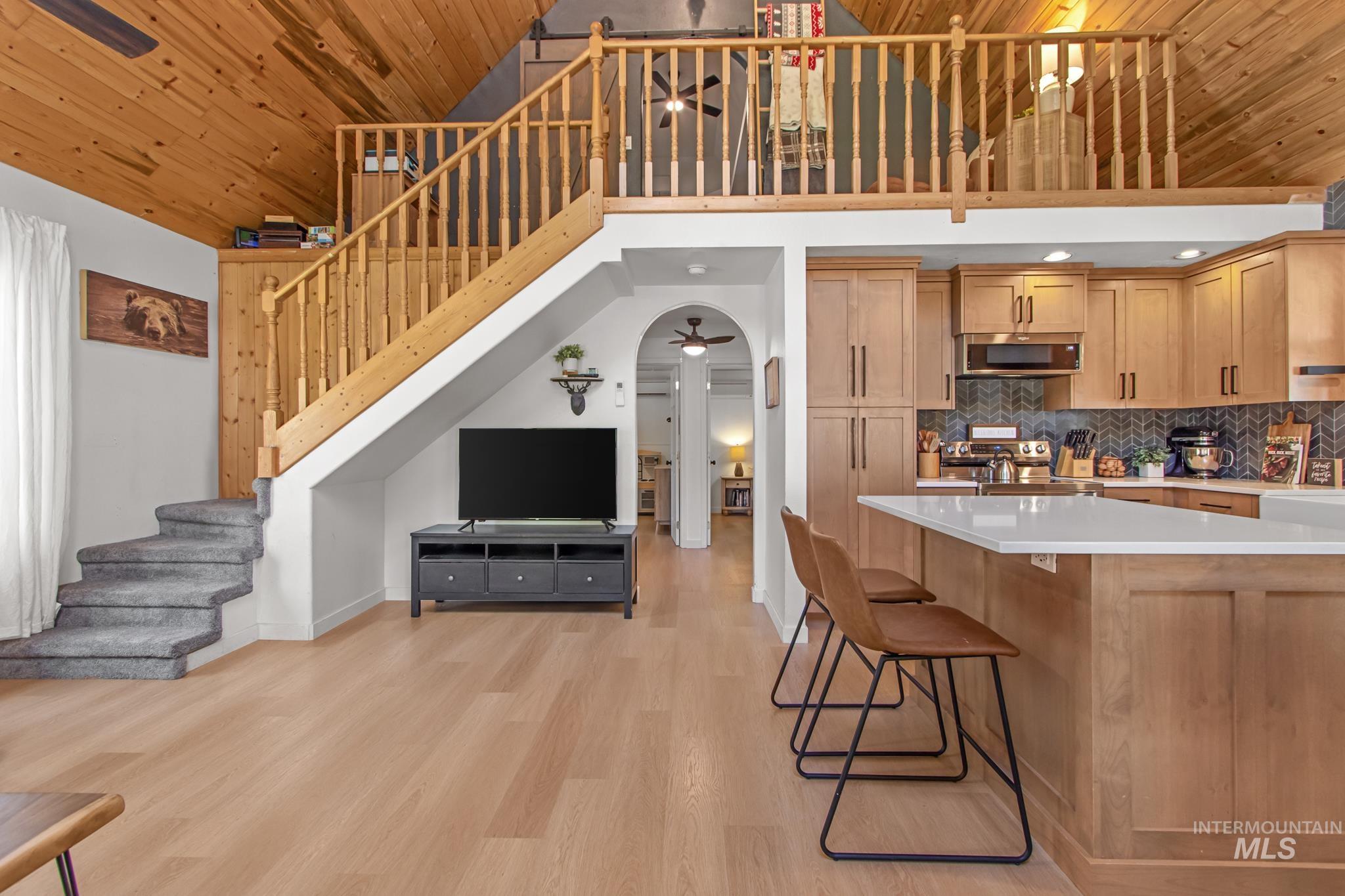 Kitchen featuring wooden ceiling, a ceiling fan, backsplash, a breakfast bar, and light wood-type flooring