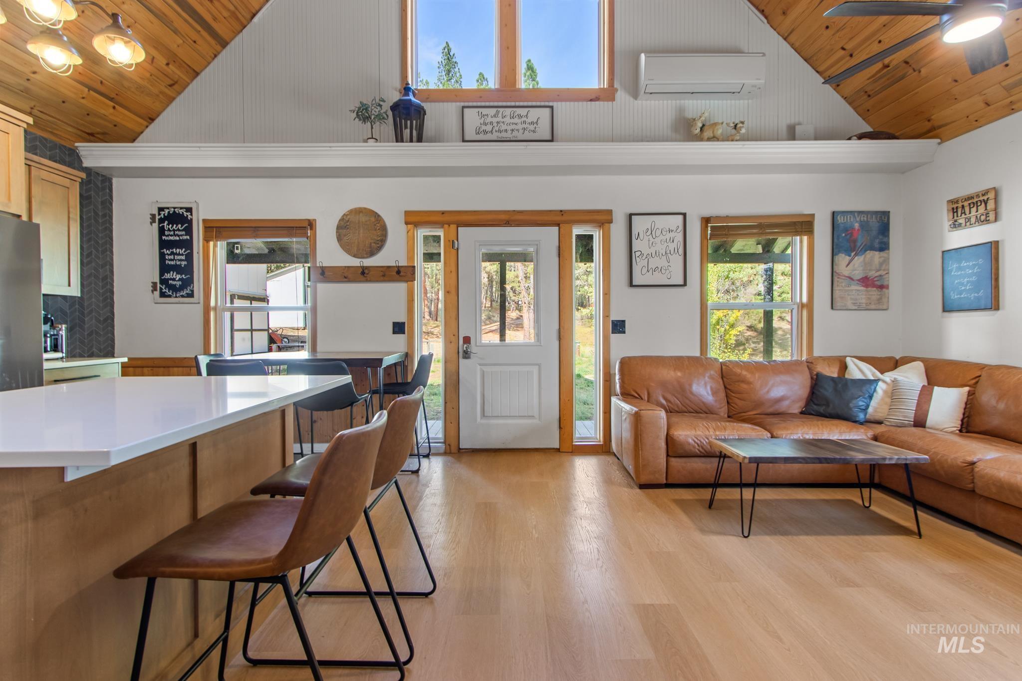 Living room with wood ceiling, light wood-style flooring, healthy amount of natural light, a ceiling fan, and an AC wall unit