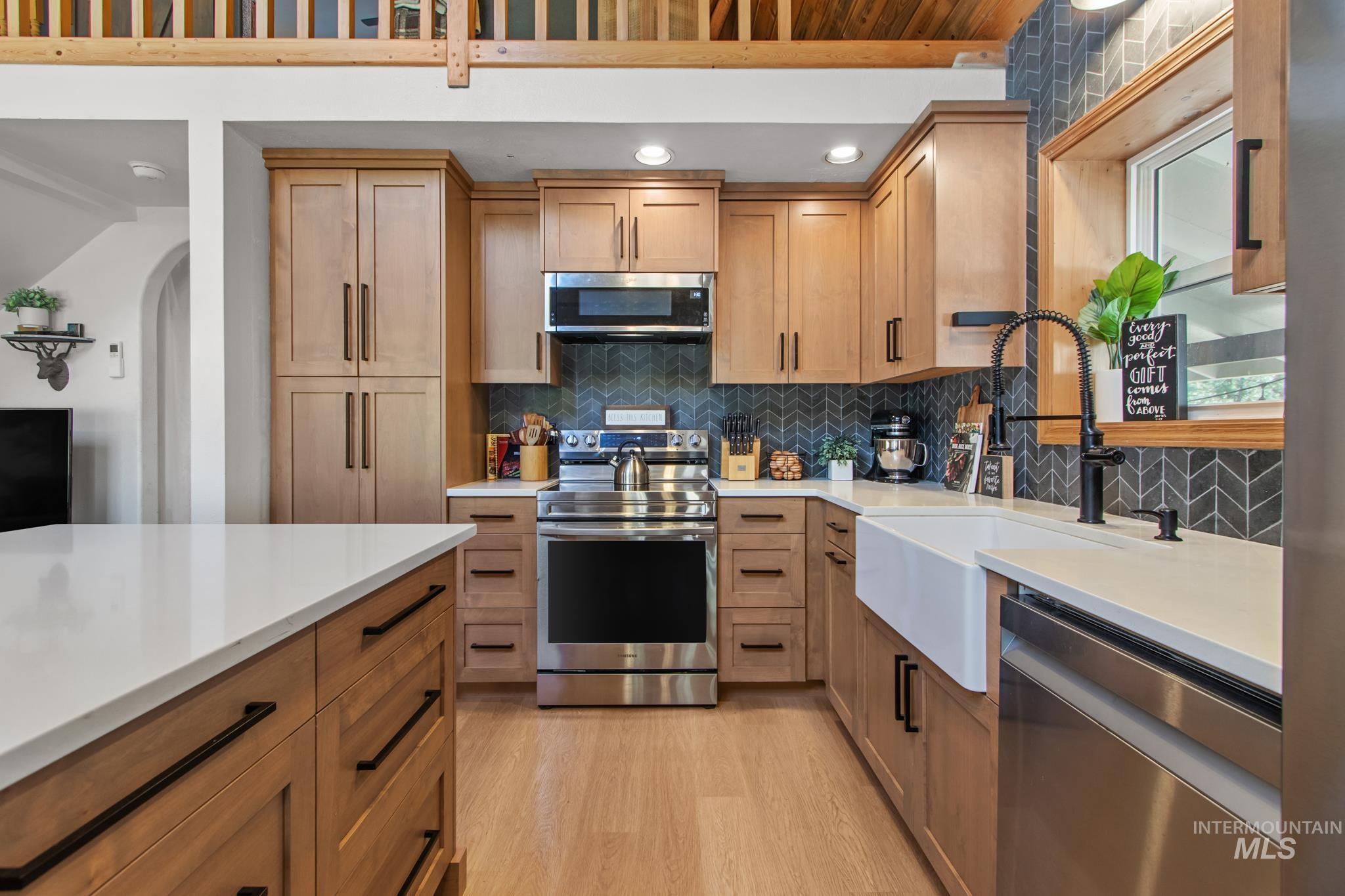 Kitchen featuring tasteful backsplash, stainless steel appliances, light wood-style flooring, brown cabinetry, and recessed lighting