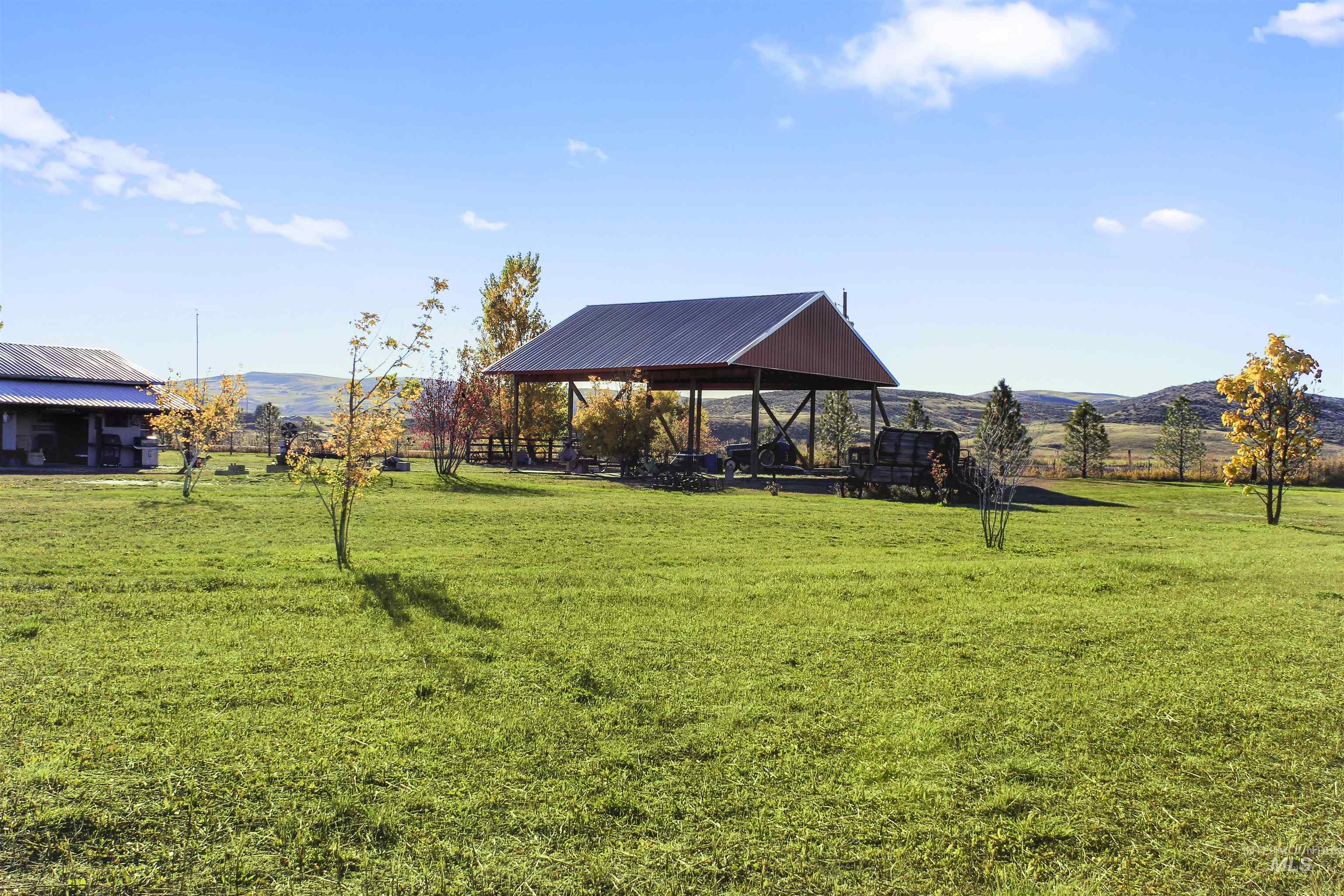 View of green lawn featuring a rural view, a mountain view, and a patio area