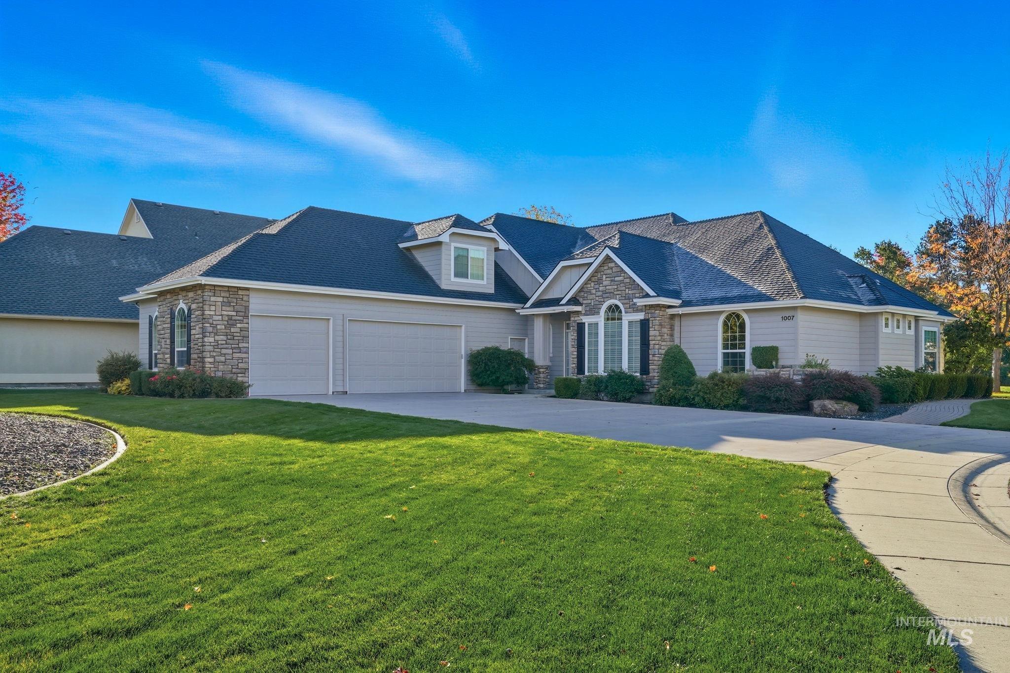 View of front facade with stone siding, a front lawn, and concrete driveway