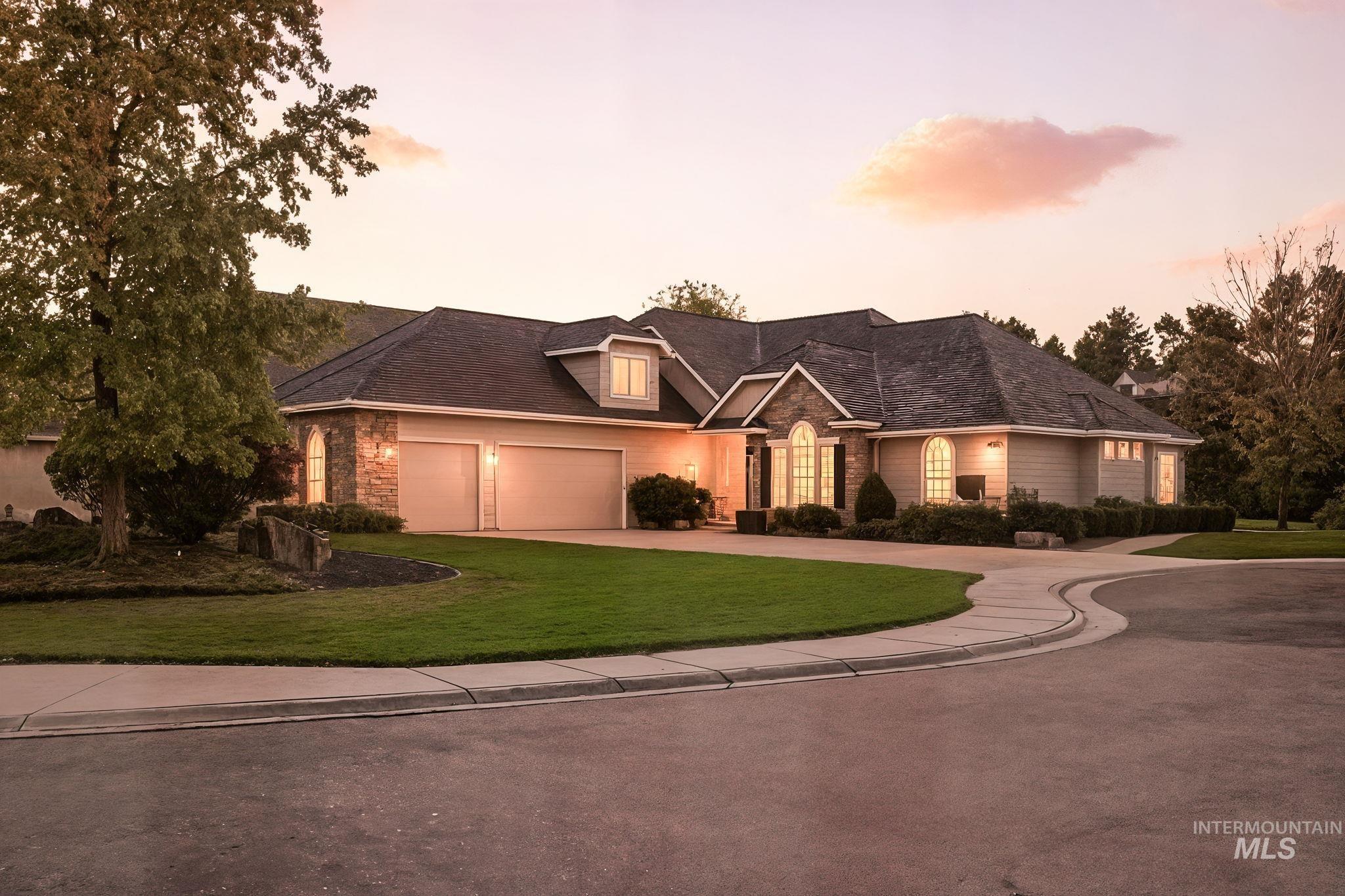 View of front of home with concrete driveway, a yard, stone siding, and a garage