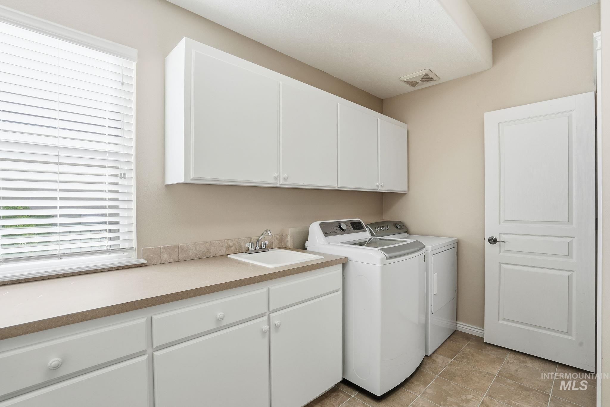 Washroom with washer and clothes dryer and cabinet space
