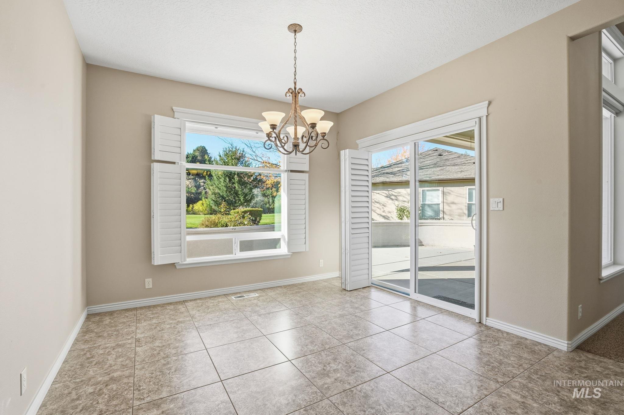 Unfurnished dining area with plenty of natural light, light tile patterned floors, and a chandelier
