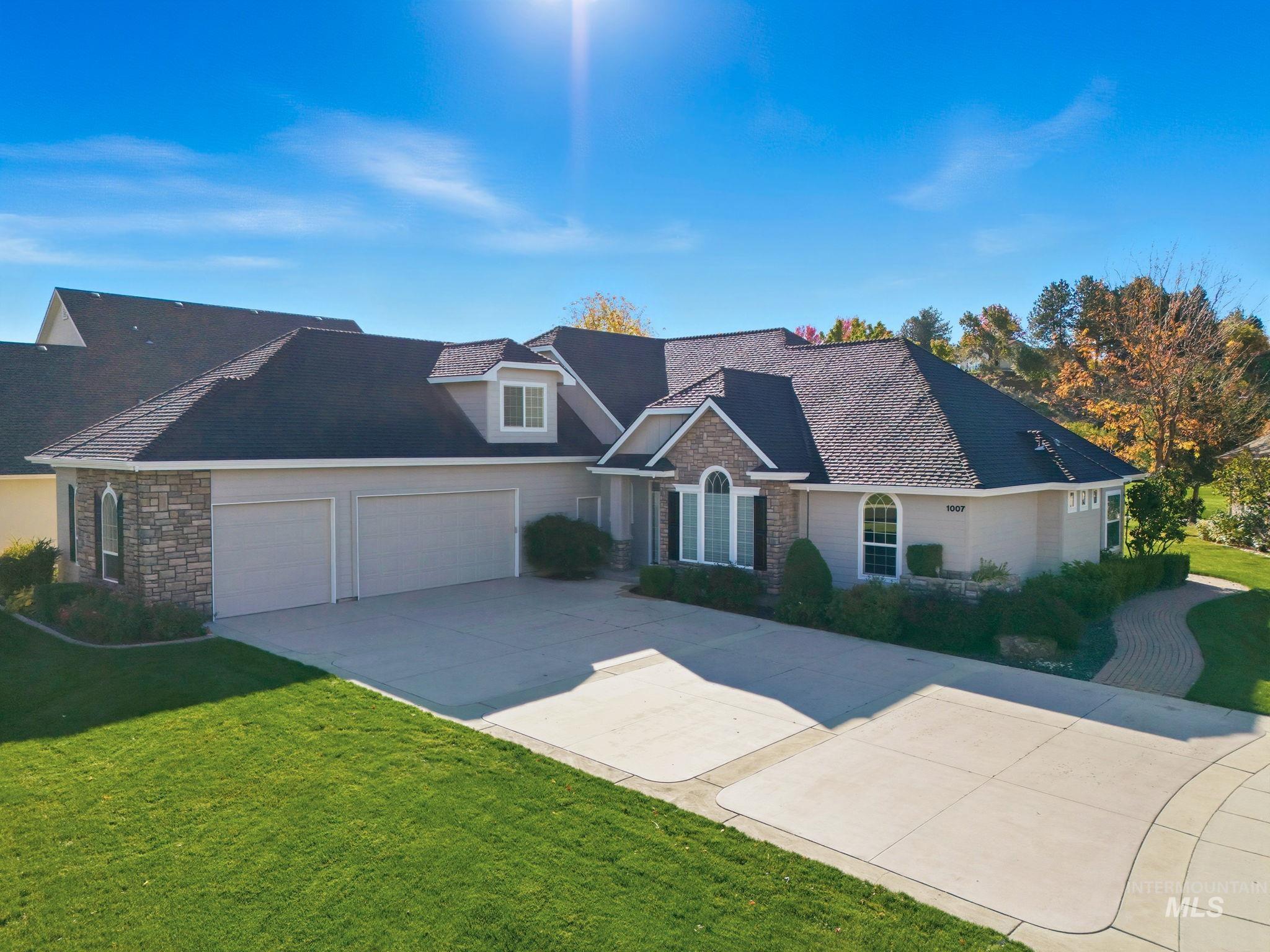View of front of house with stone siding, a front yard, concrete driveway, and an attached garage