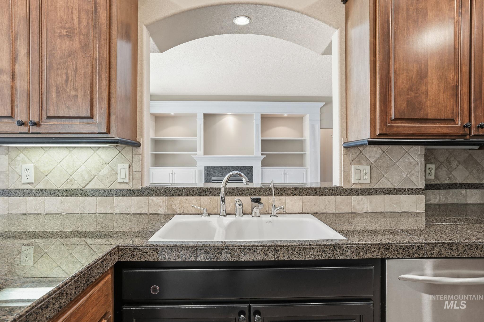 Kitchen with tile countertops, tasteful backsplash, and stainless steel dishwasher