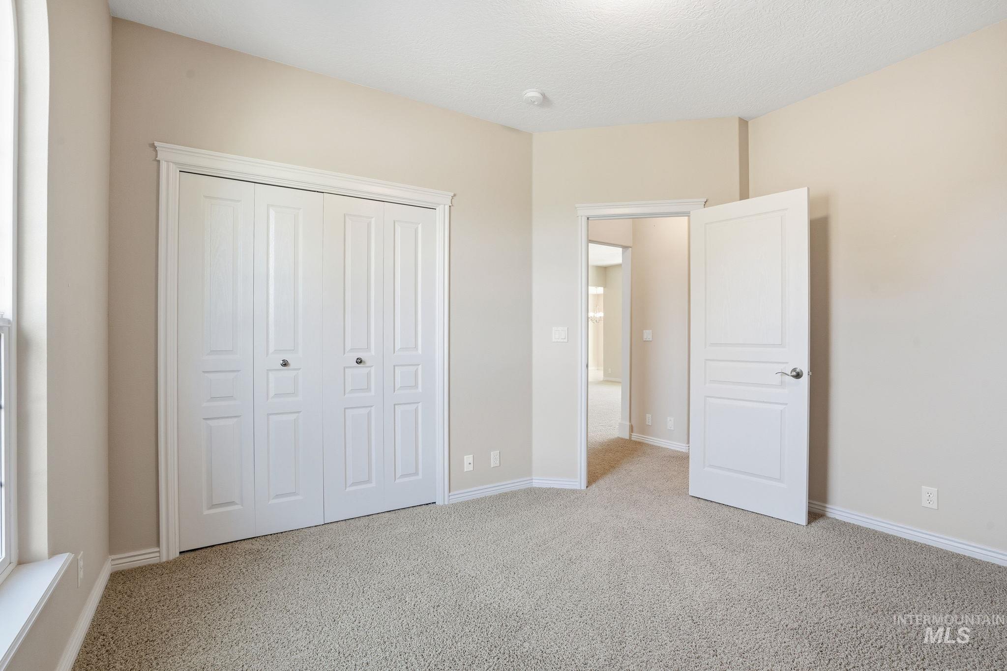 Unfurnished bedroom with light colored carpet, a closet, and a textured ceiling
