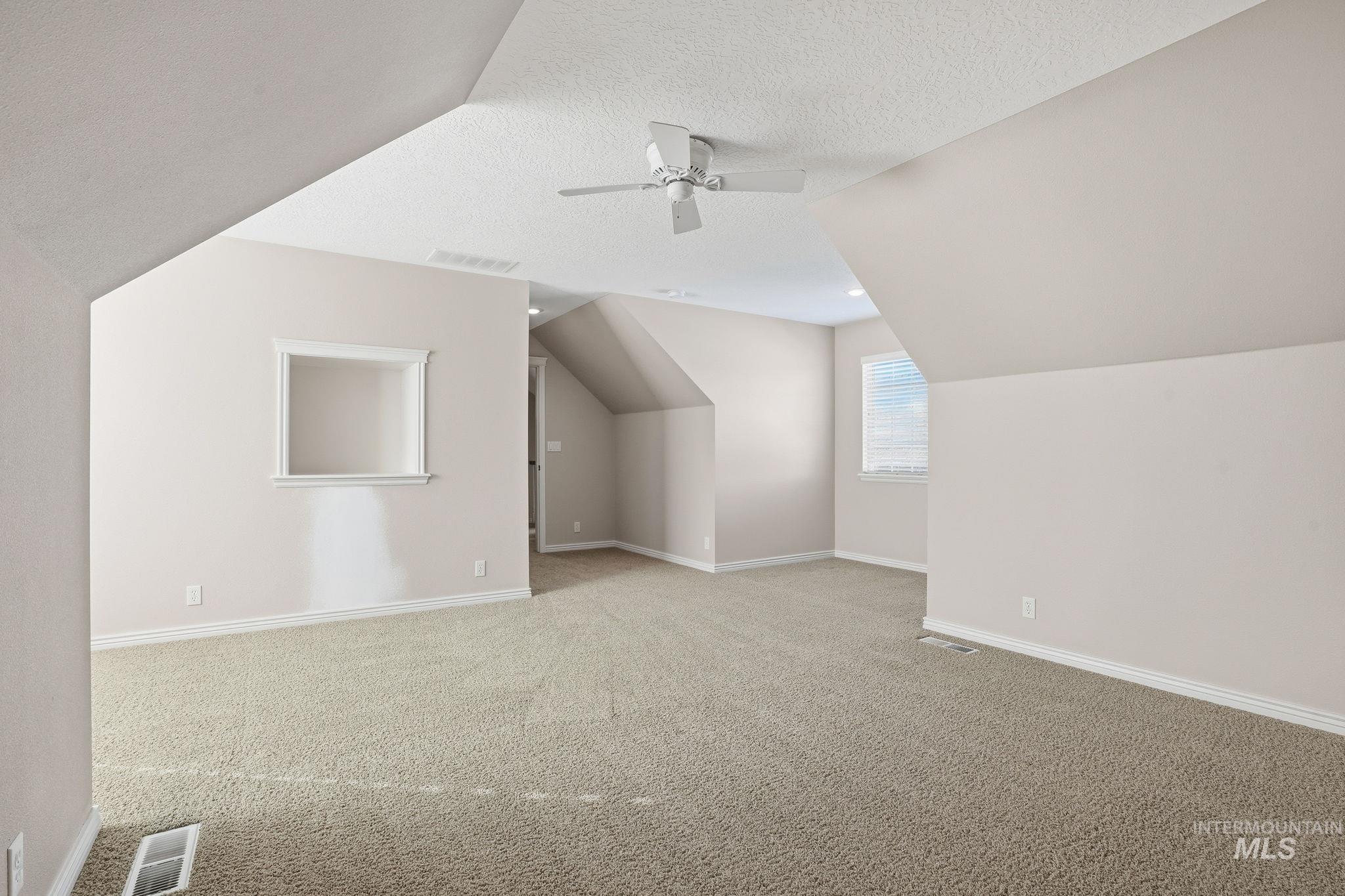 Additional living space with a textured ceiling, carpet, lofted ceiling, and a ceiling fan