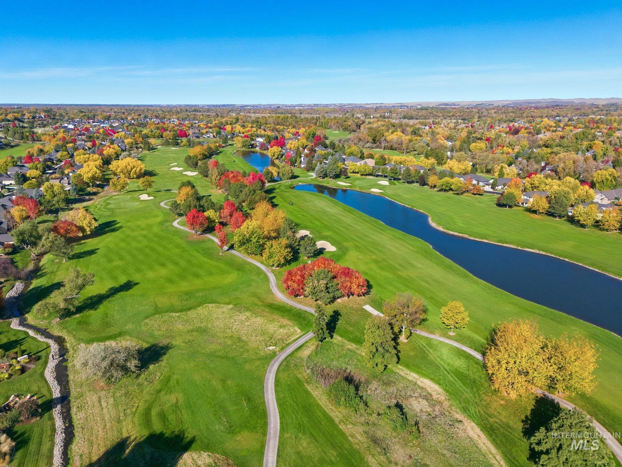 Aerial view of property's location featuring a large body of water, a local golf course, and nearby suburban area