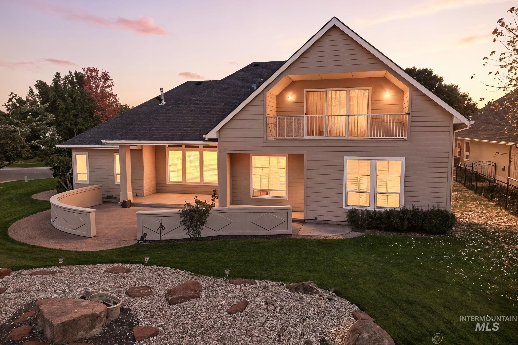 Back of house at dusk featuring a patio and a balcony