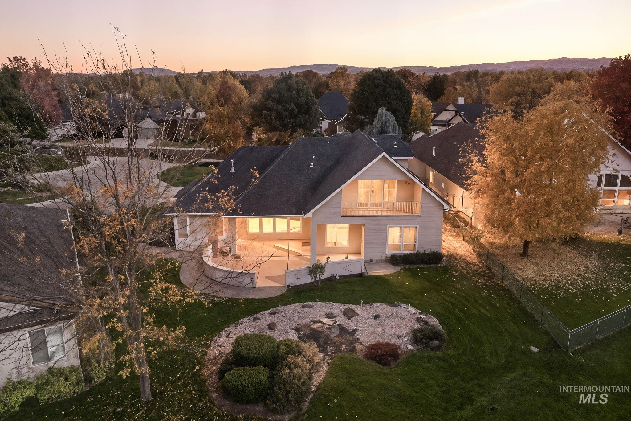 Back of house at dusk with a balcony, a fenced backyard, and a patio area