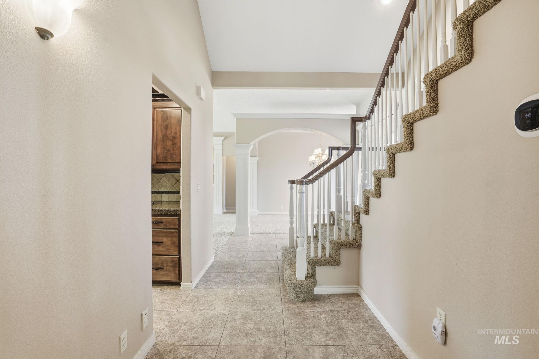 Entryway featuring light tile patterned floors, a chandelier, and arched walkways