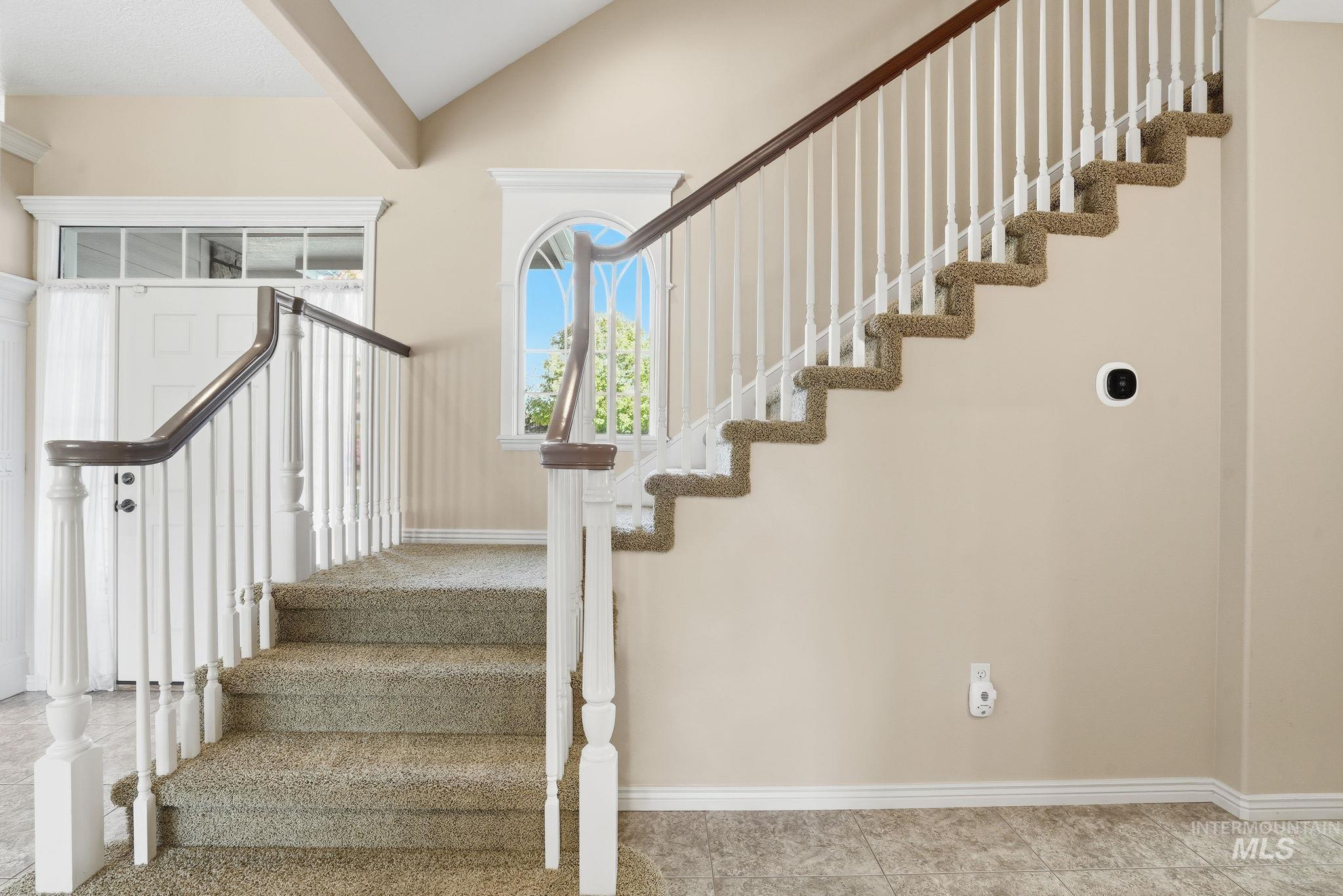 Stairway featuring vaulted ceiling and tile patterned floors