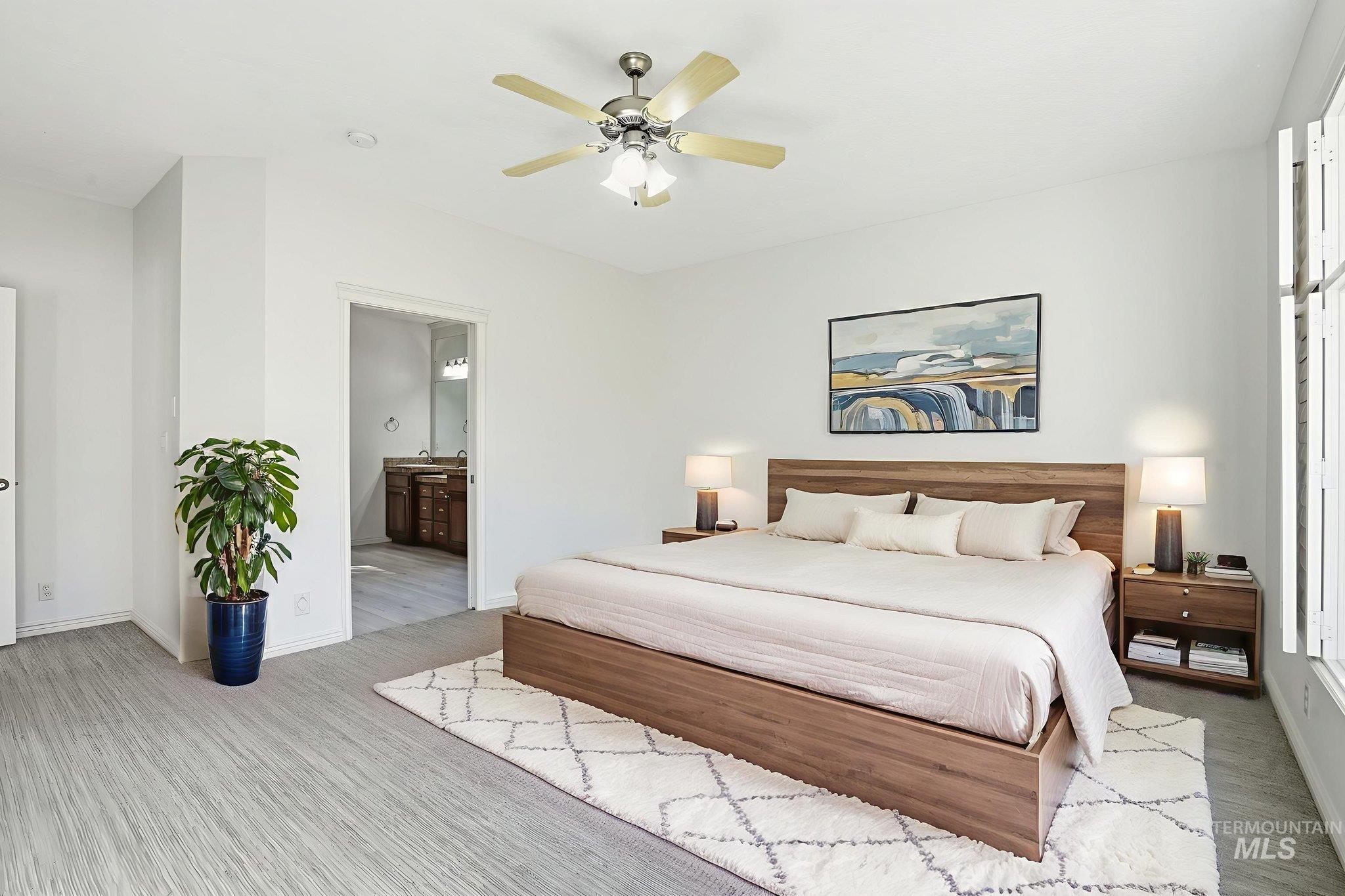 Bedroom with light wood finished floors, ceiling fan, and connected bathroom