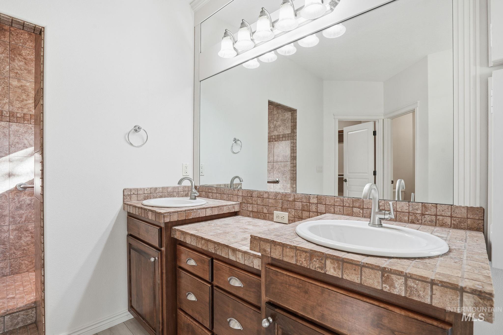 Bathroom featuring double vanity and tiled shower