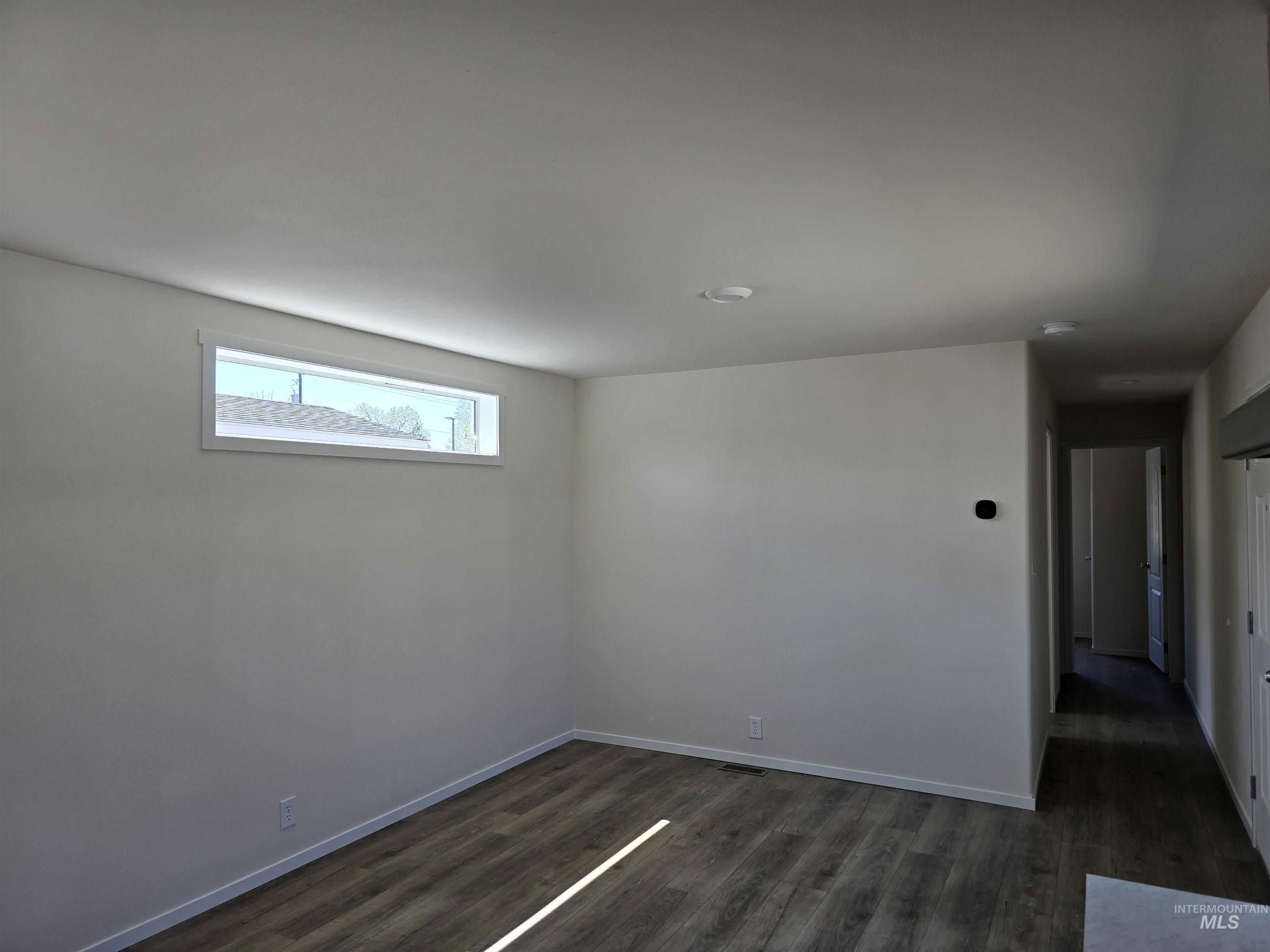 Unfurnished room featuring dark wood-type flooring and baseboards