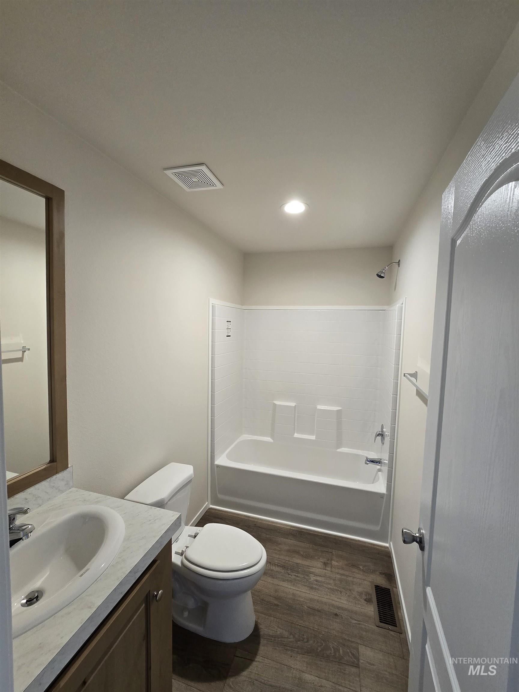 Full bath with dark wood finished floors, vanity, bathtub / shower combination, and recessed lighting