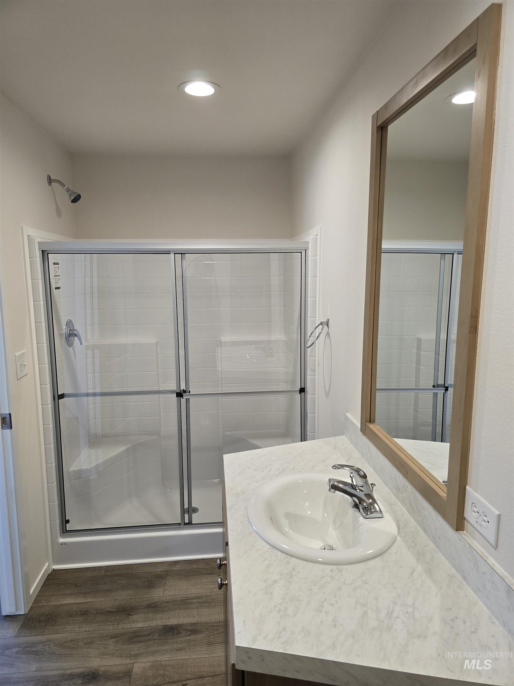 Full bath featuring vanity, dark wood-style flooring, recessed lighting, and a stall shower