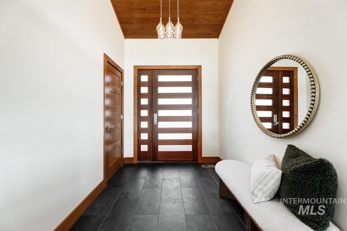 Foyer with wood ceiling, vaulted ceiling, and a chandelier