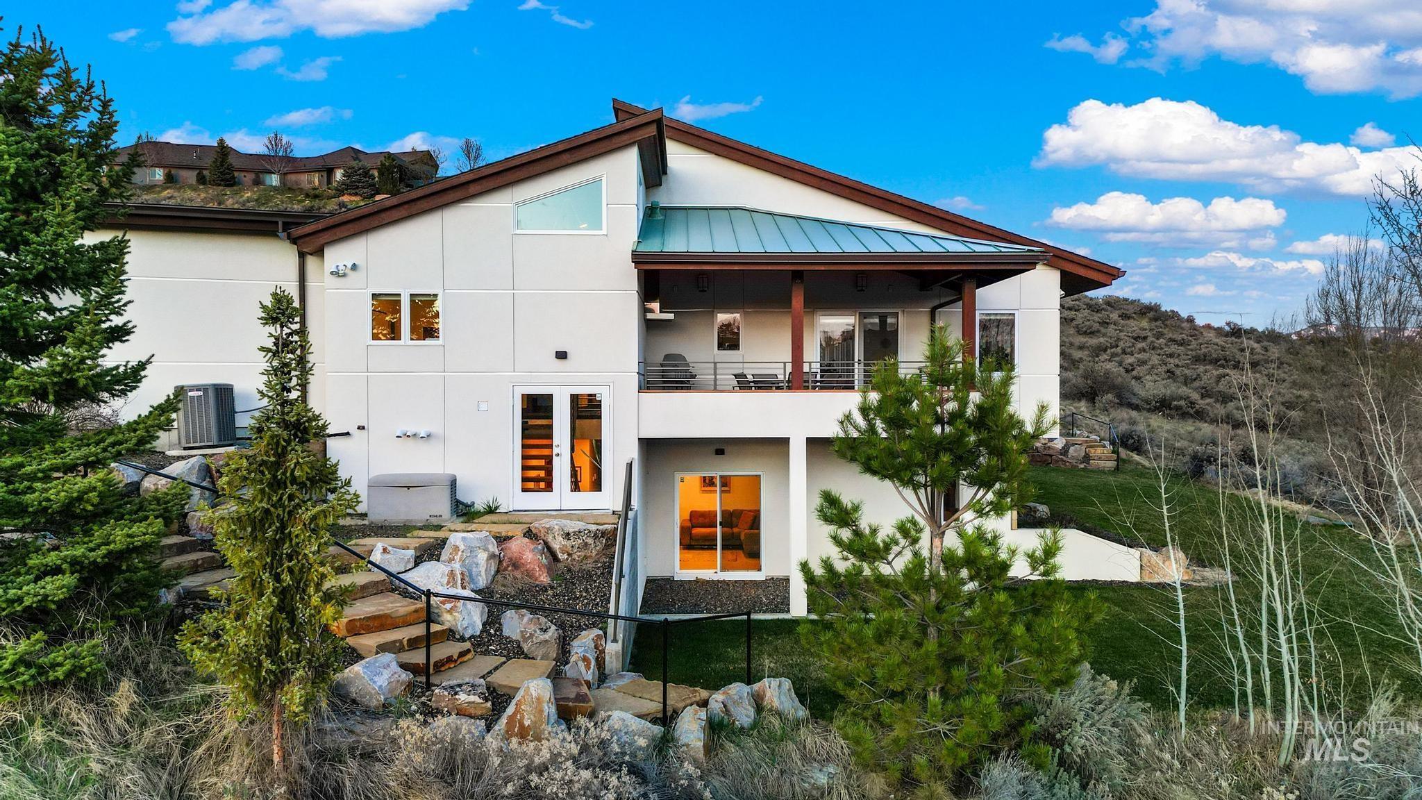 Rear view of house with a standing seam roof, a balcony, a metal roof, and stucco siding