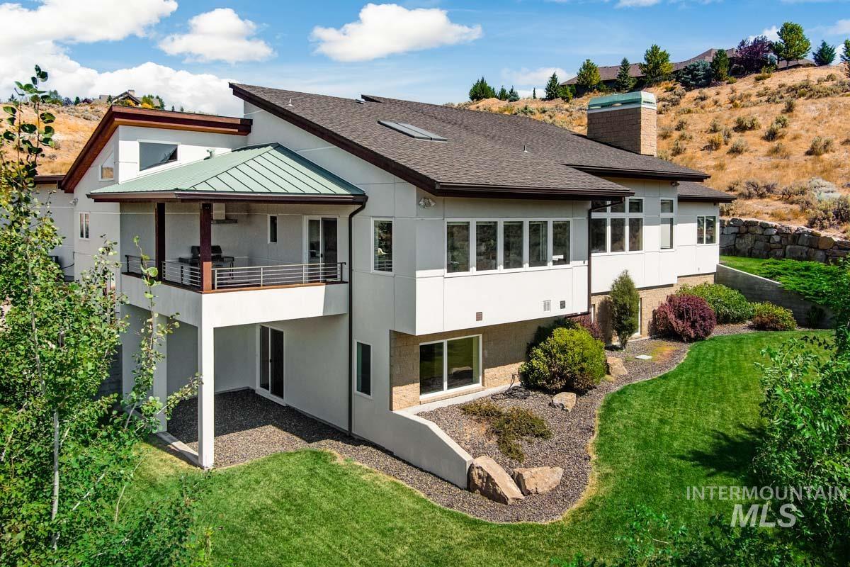 Rear view of property featuring a standing seam roof, a chimney, a lawn, a metal roof, and a patio area