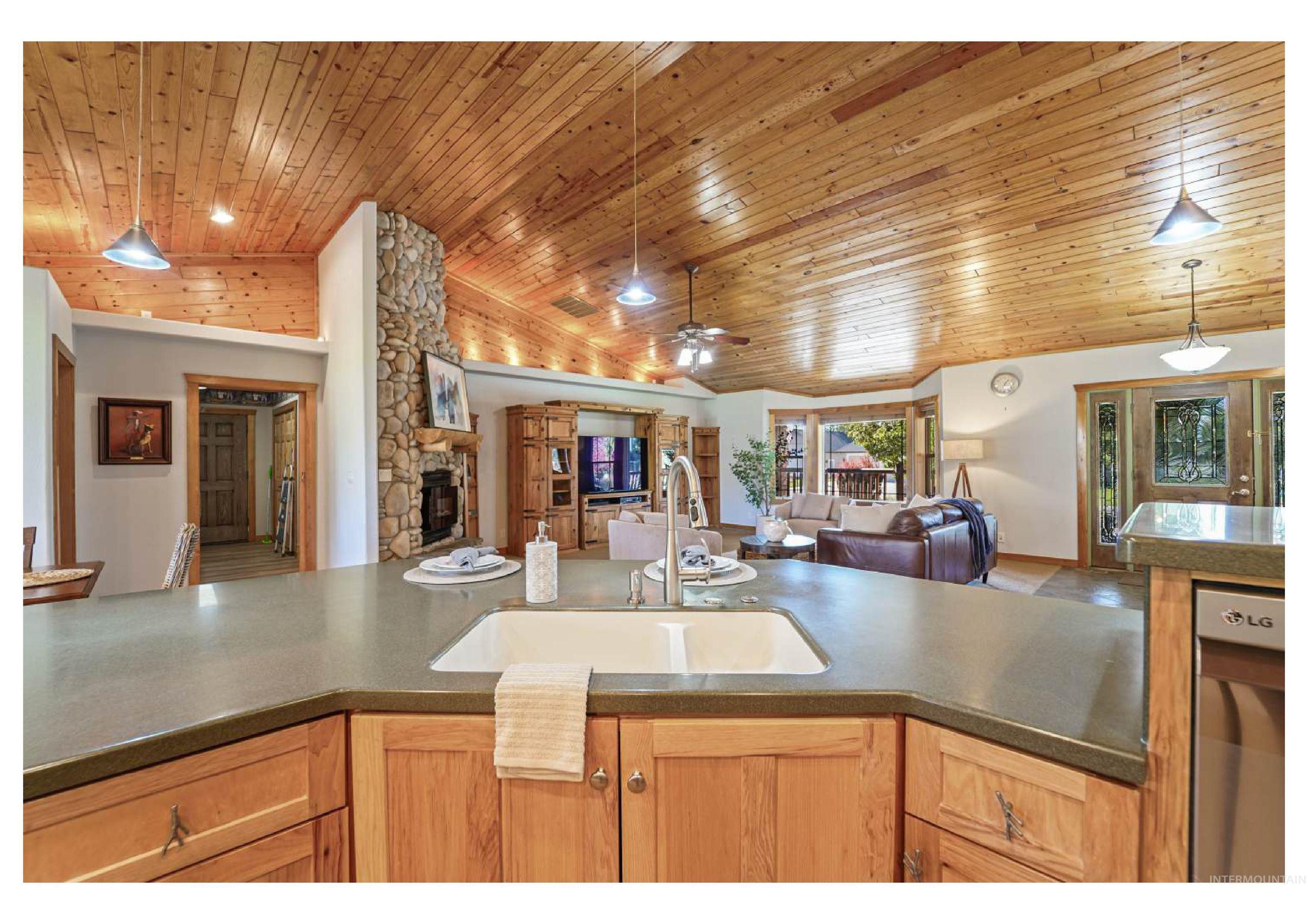 Kitchen with hanging light fixtures, open floor plan, ceiling fan, wood ceiling, and a fireplace