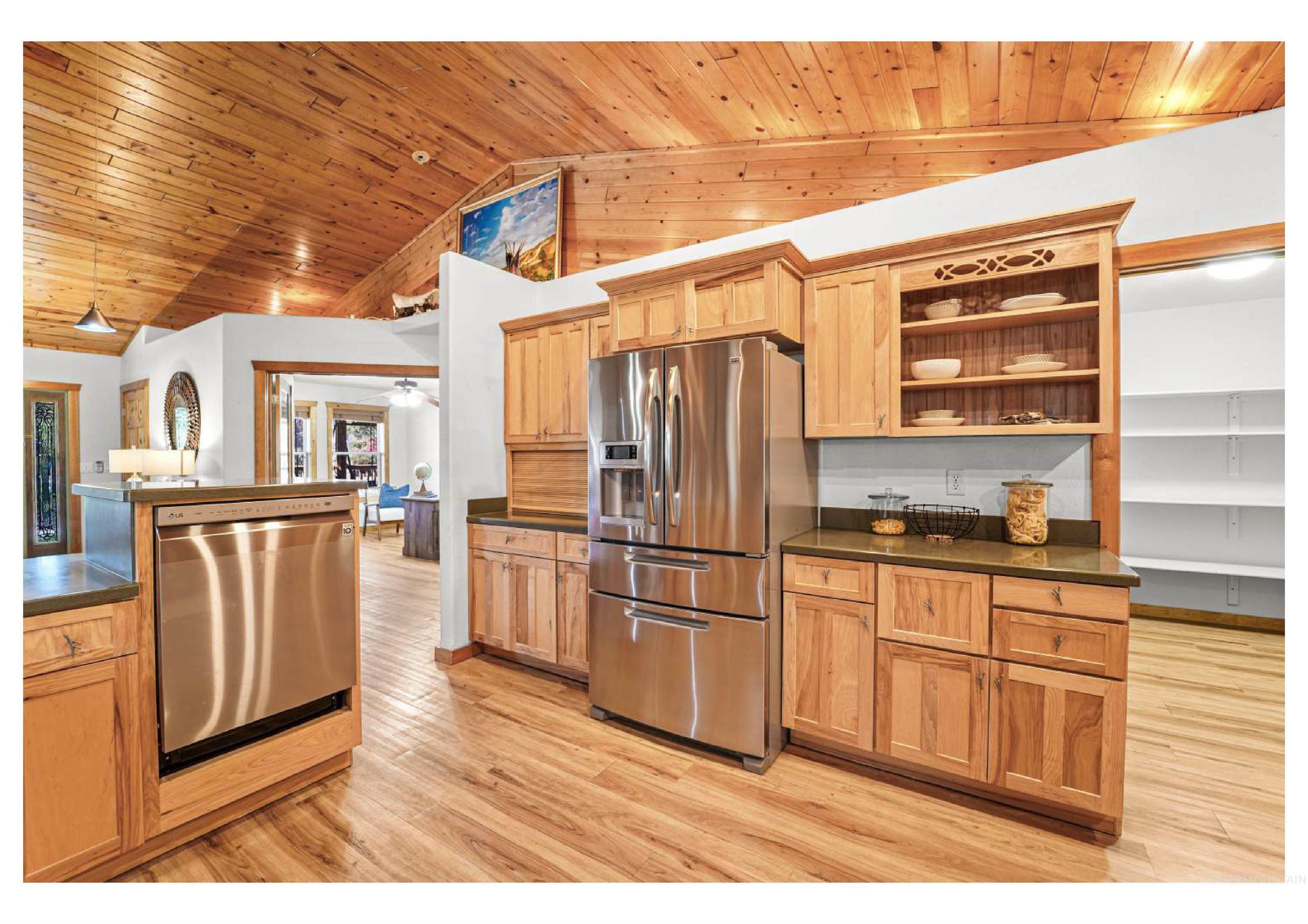 Kitchen with stainless steel appliances, light wood-style flooring, open shelves, hanging light fixtures, and wood ceiling