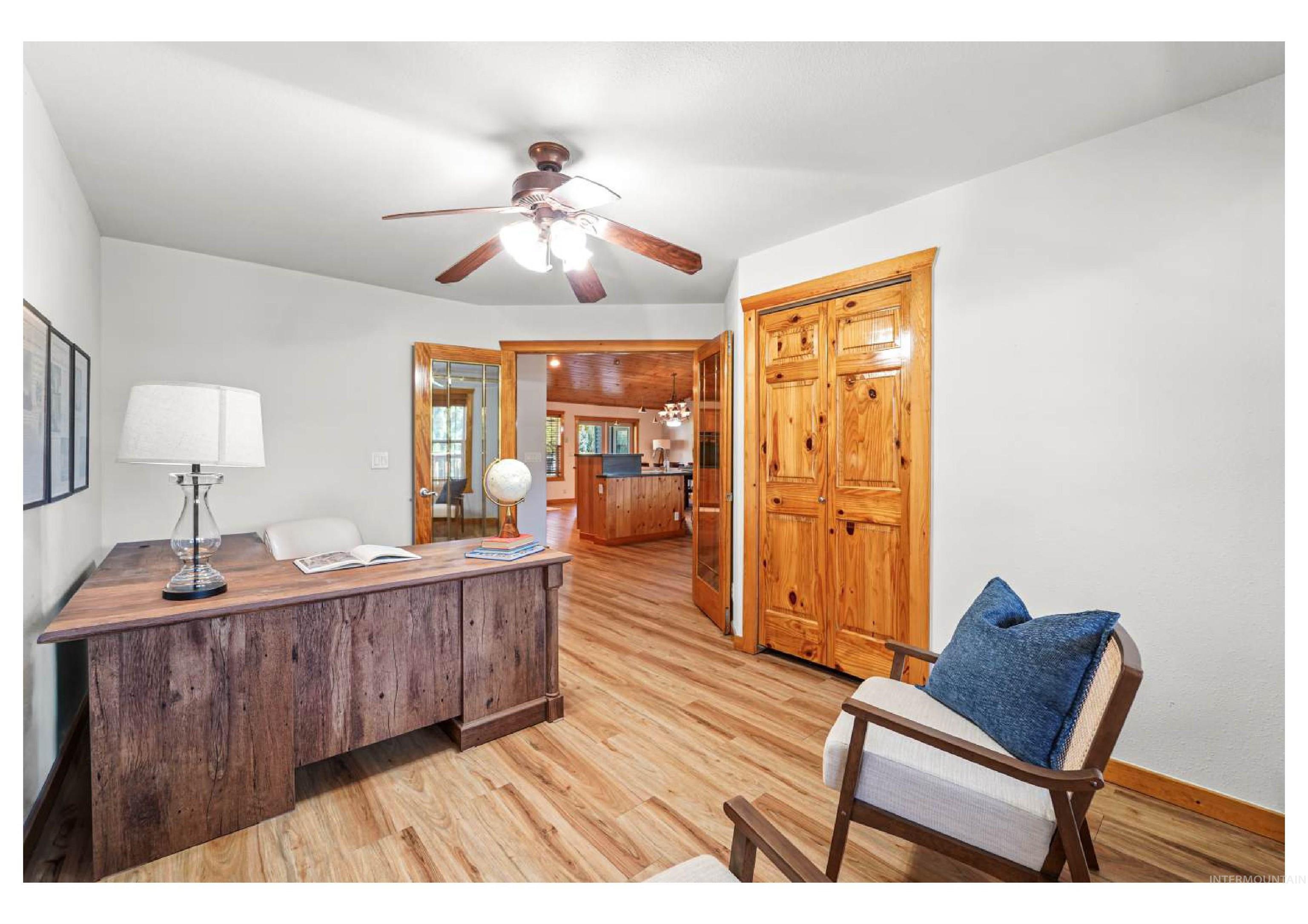 Office with light wood-type flooring and ceiling fan
