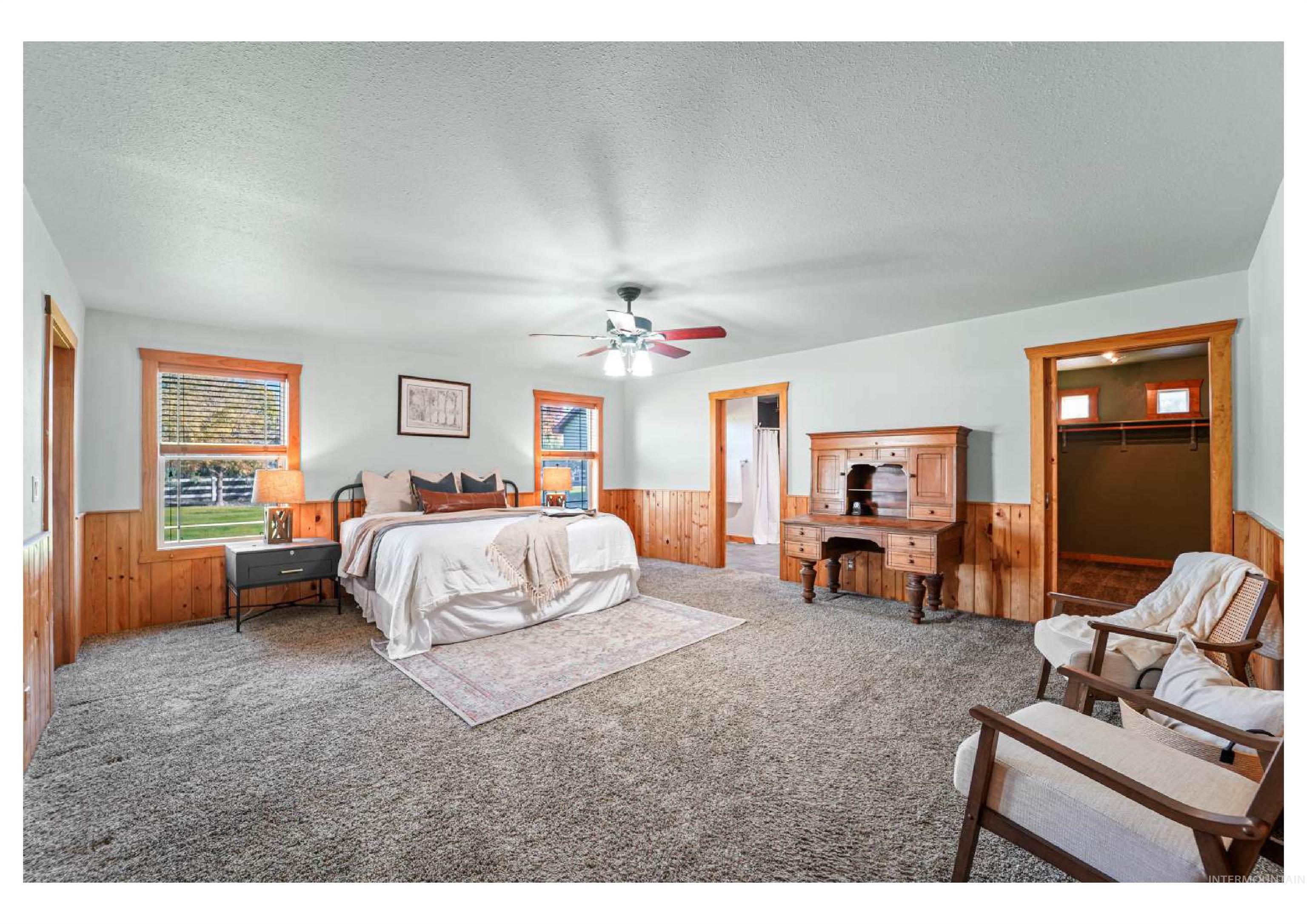 Carpeted bedroom featuring wooden walls, a wainscoted wall, a textured ceiling, a ceiling fan, and a spacious closet