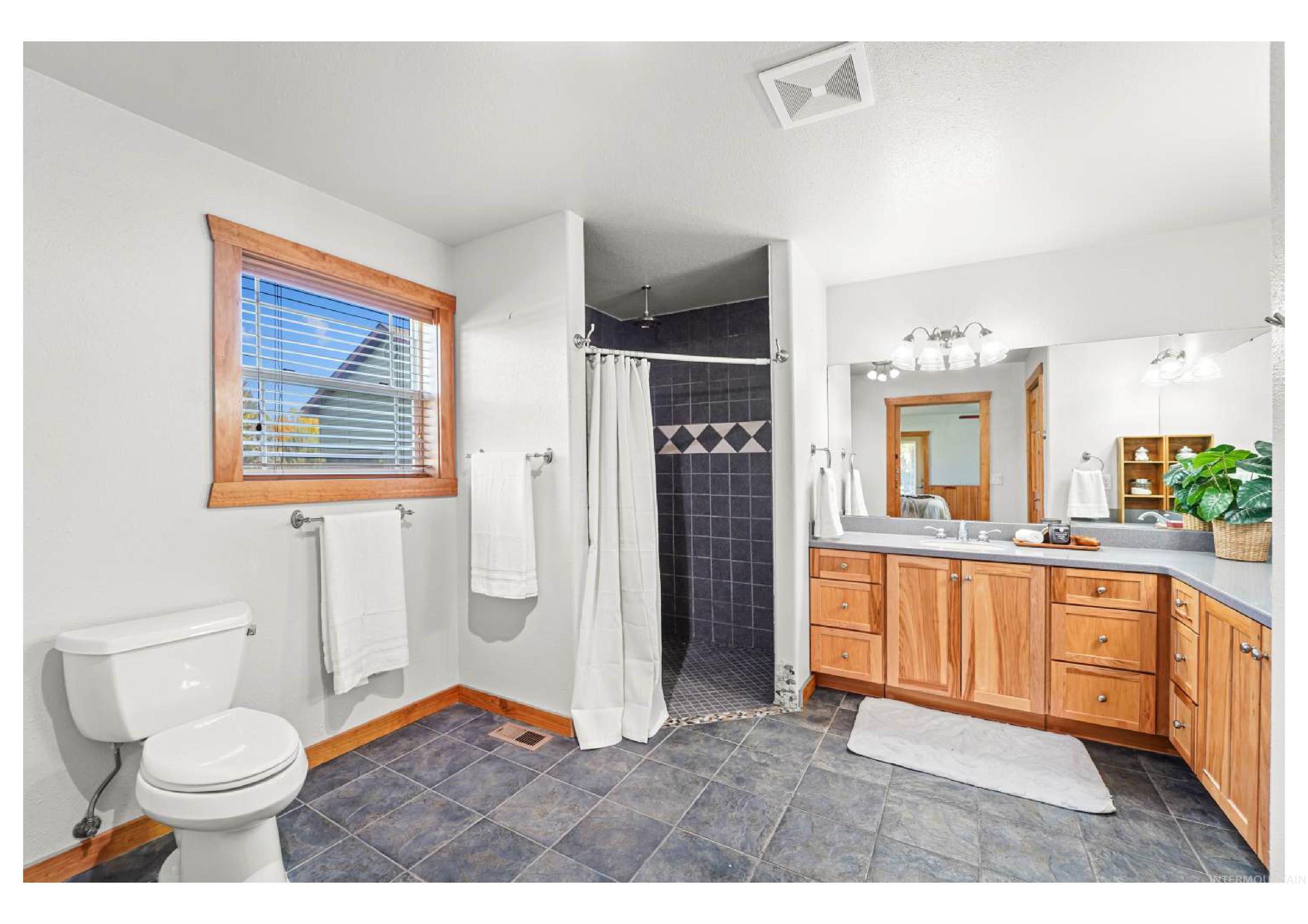 Bathroom with a stall shower, vanity, and dark tile patterned flooring