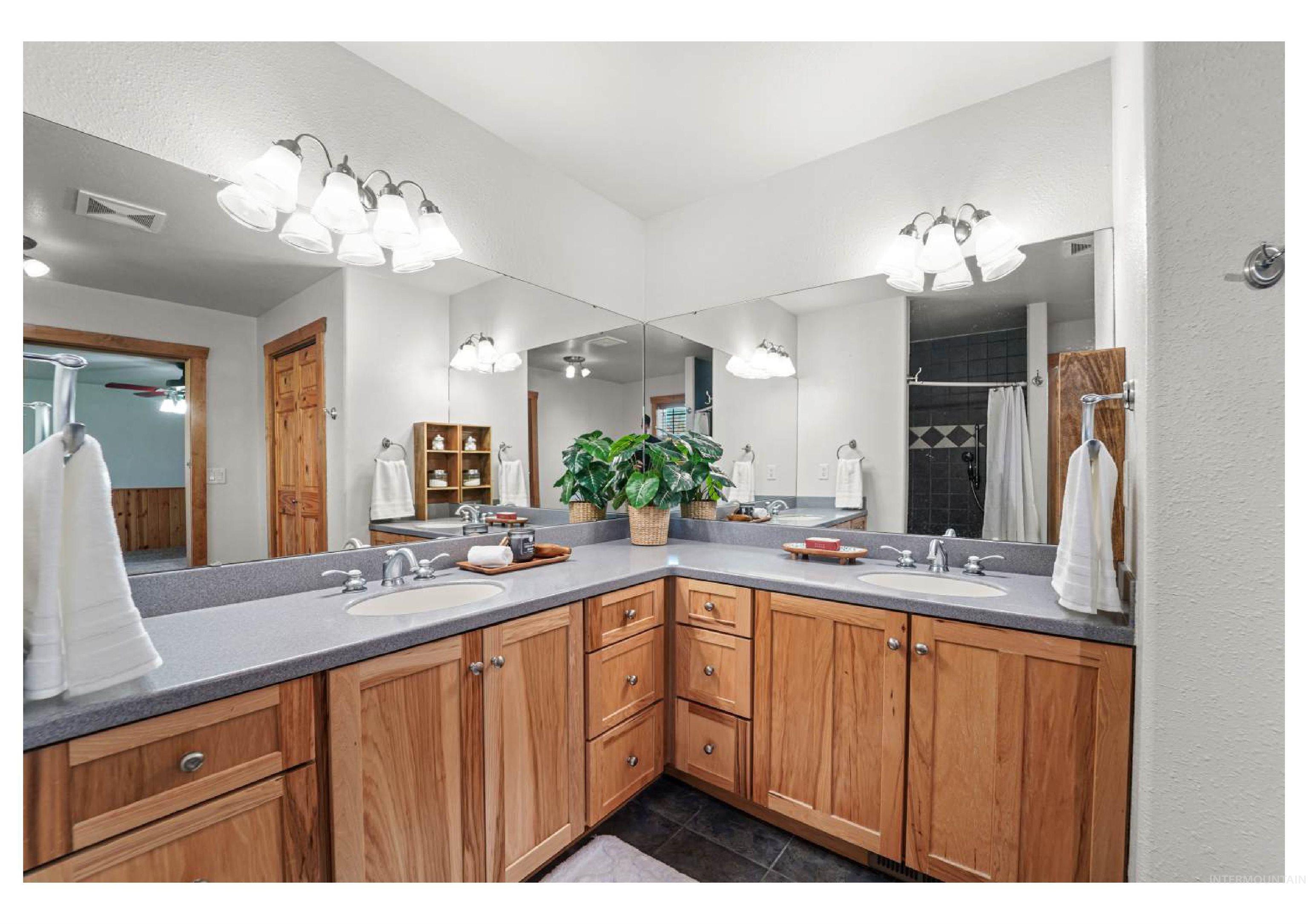 Bathroom featuring double vanity, a tile shower, dark tile patterned flooring, and ceiling fan