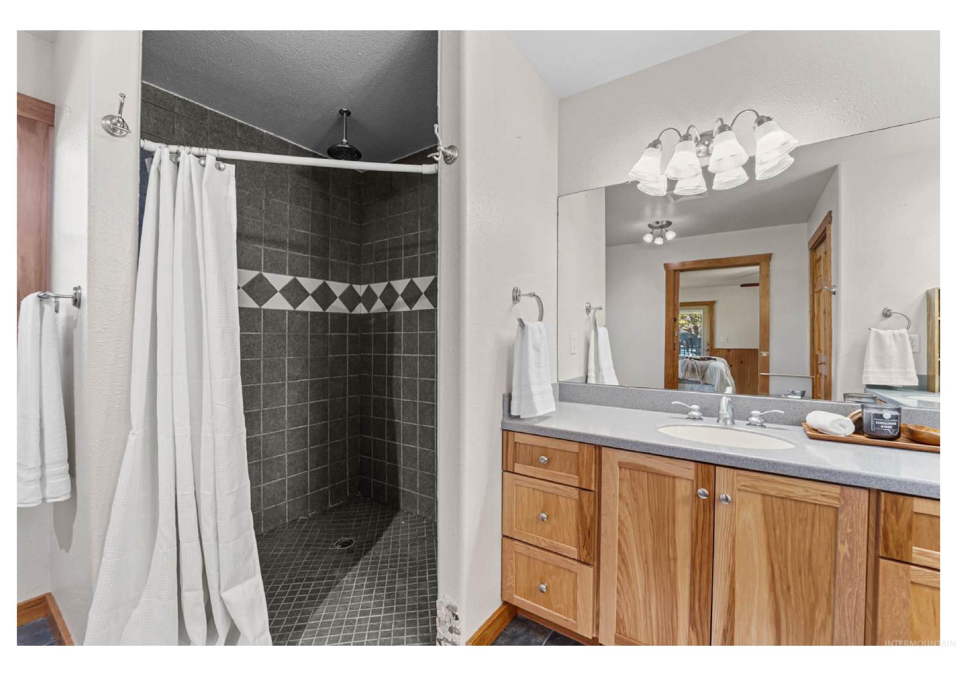 Ensuite bathroom featuring vanity, dark tile patterned flooring, and a stall shower