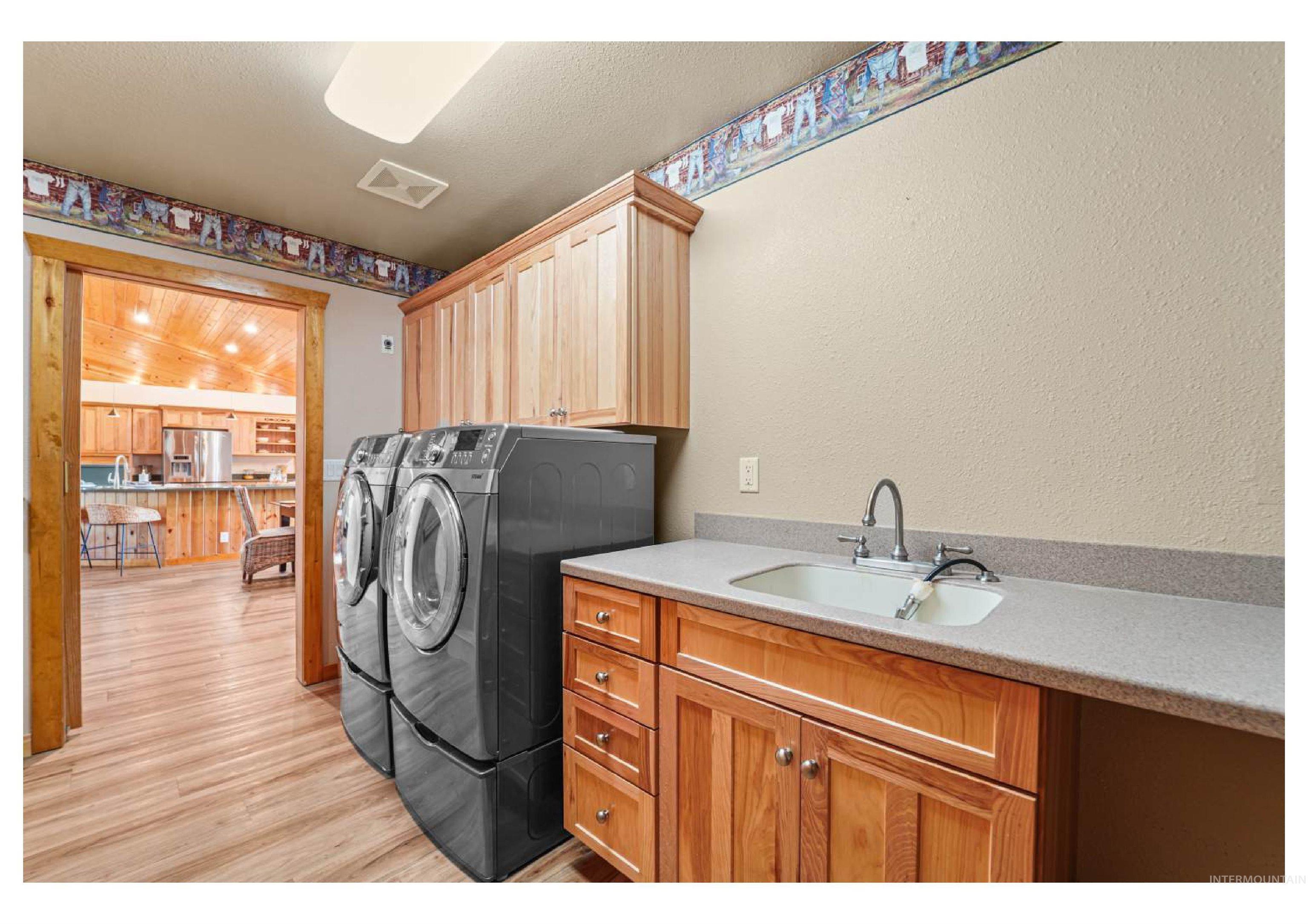 Washroom with light wood-style floors, cabinet space, a textured wall, and washer and dryer