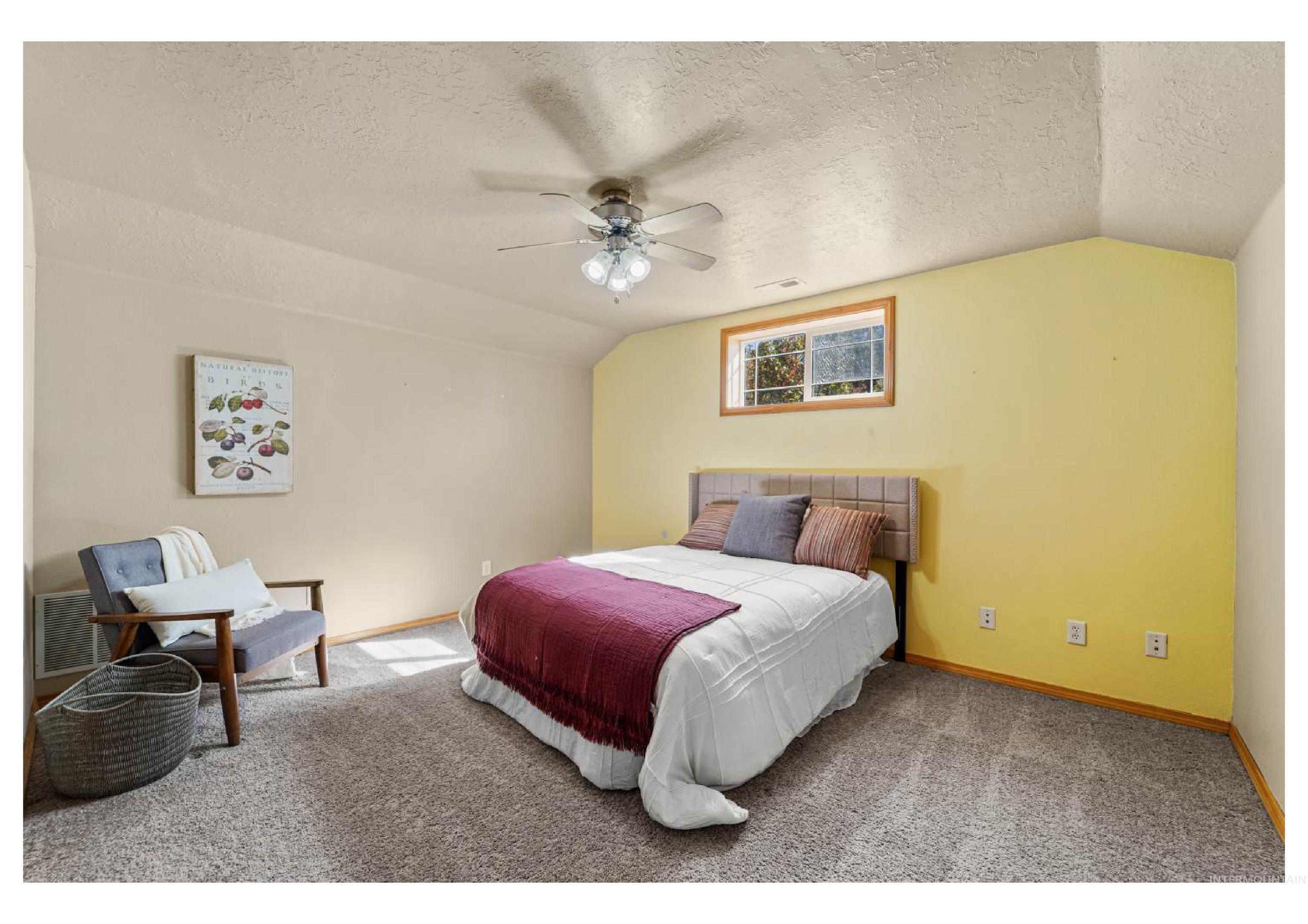 Carpeted bedroom featuring a textured ceiling, vaulted ceiling, and ceiling fan