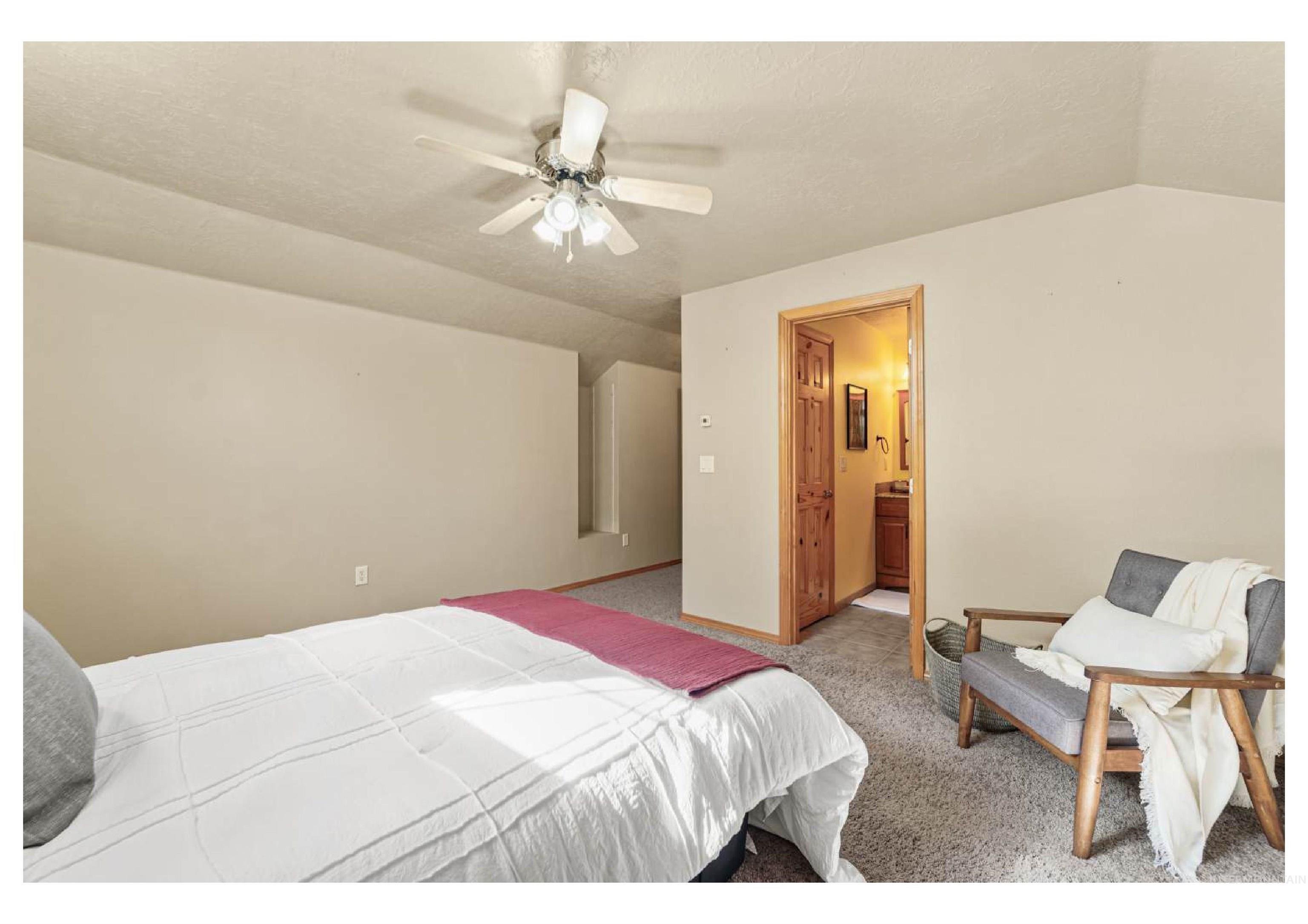 Bedroom featuring carpet flooring, lofted ceiling, a ceiling fan, connected bathroom, and a textured ceiling