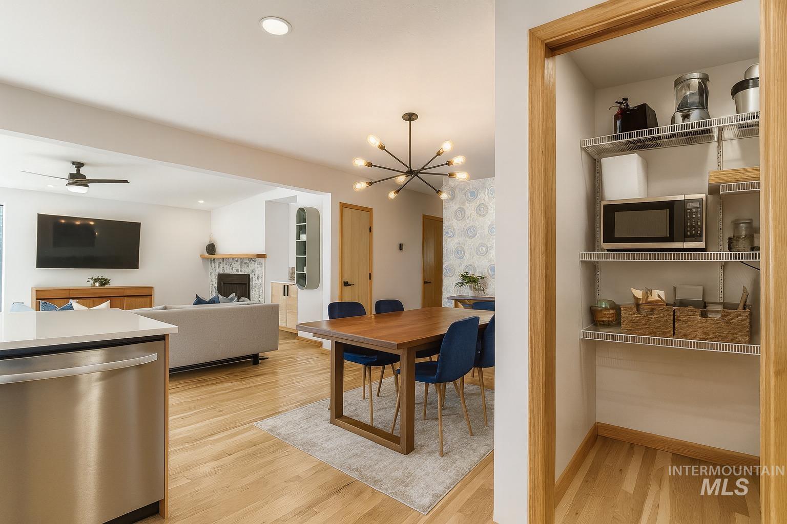 Dining room with a fireplace, light wood finished floors, a chandelier, ceiling fan, and recessed lighting