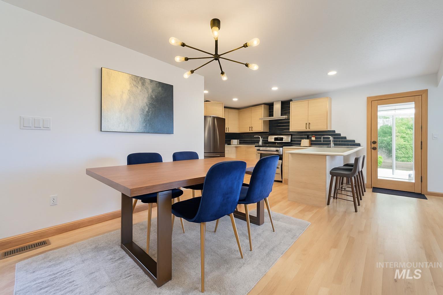Dining room with light wood finished floors, a chandelier, and recessed lighting