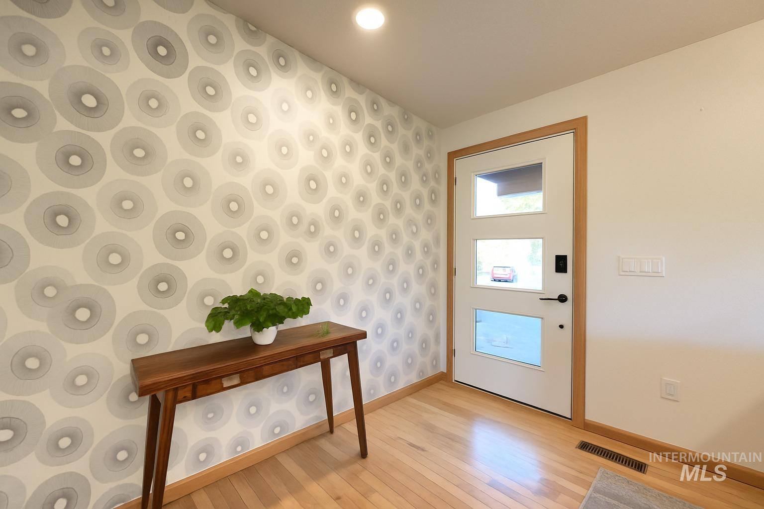 Doorway to outside with wood-type flooring, wallpapered walls, and recessed lighting