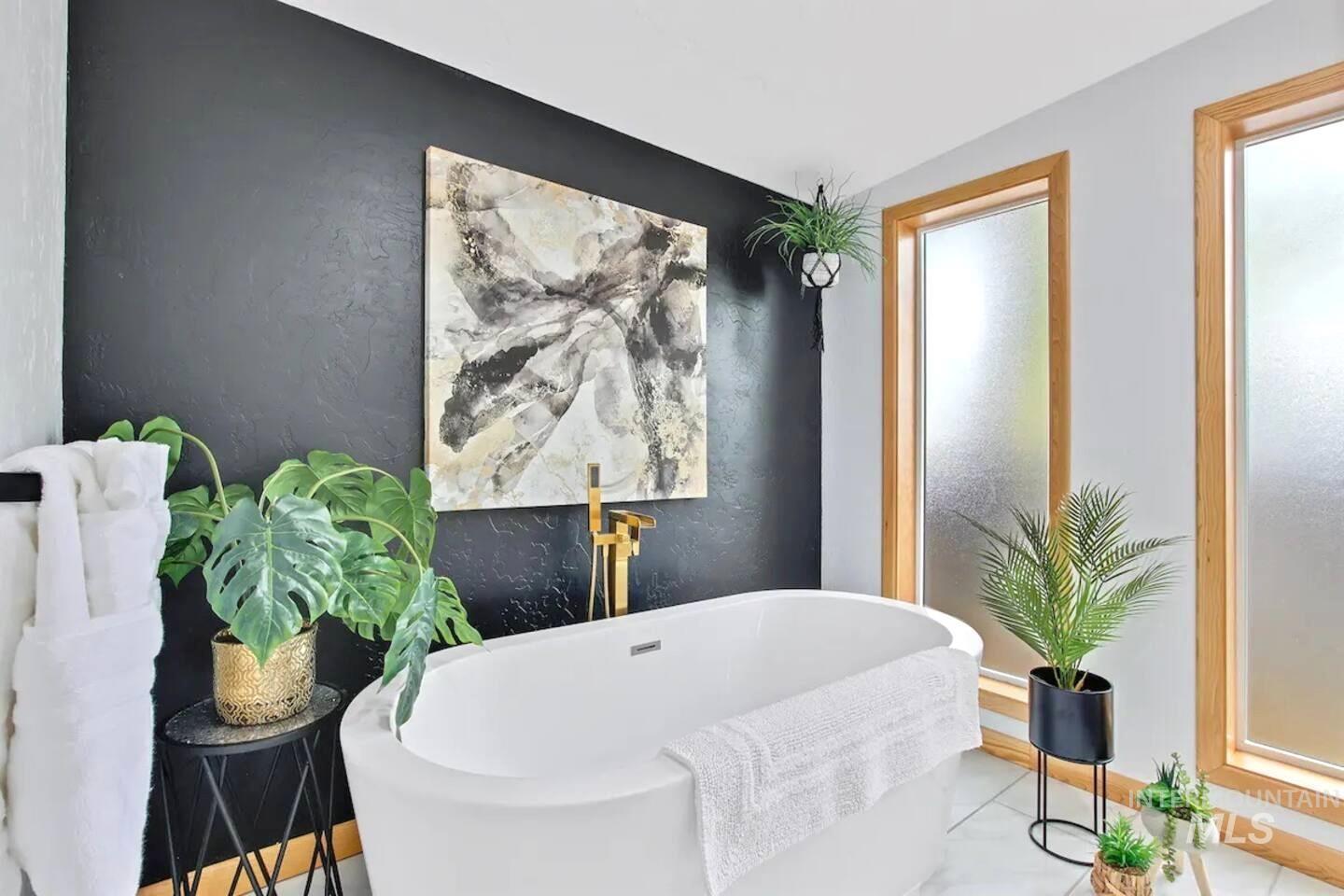 Full bath featuring a textured wall, a freestanding bath, and tile patterned floors