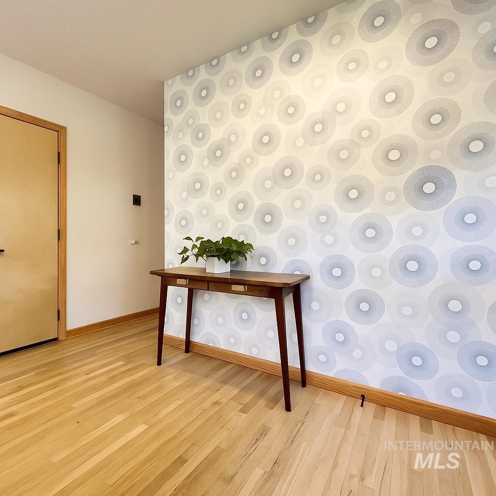 Hallway featuring light wood finished floors and wallpapered walls