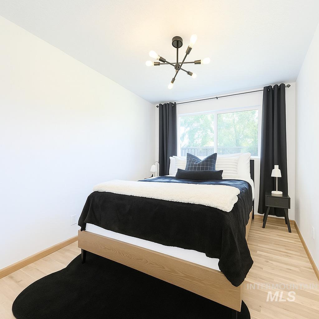 Bedroom with light wood finished floors and a chandelier