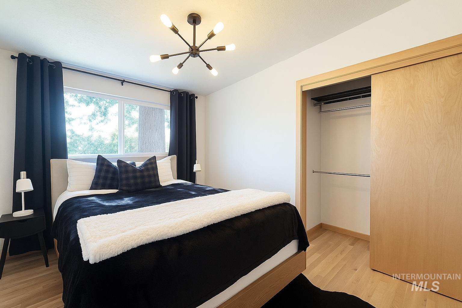 Bedroom with light wood-type flooring, a chandelier, and a closet
